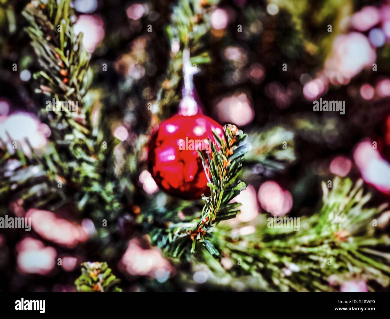 Close-up of red bauble hanging from illuminated Christmas tree. Focus on foreground. - Smartphone Captured Stock Image
