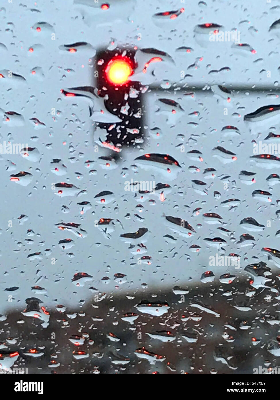 Red traffic light viewed through a wet glass - Smartphone Captured Stock Image