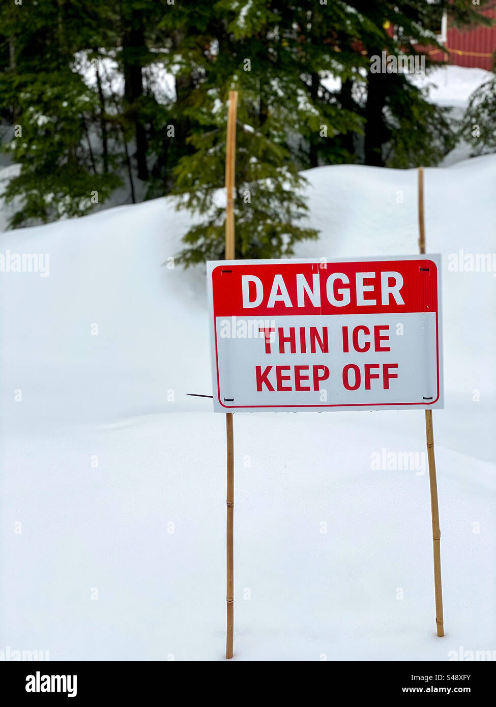 Outdoor sign in winter snow, warning of the danger of thin ice Stock Photo