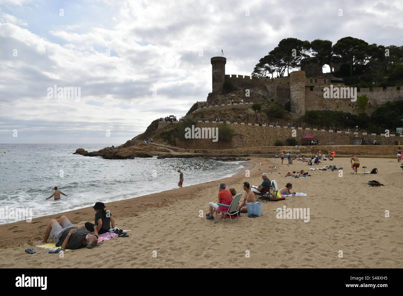 Main beach, tourists sunbathing and castle in Tossa de Mar, Costa Brava, Spain - Smartphone Captured Stock Image