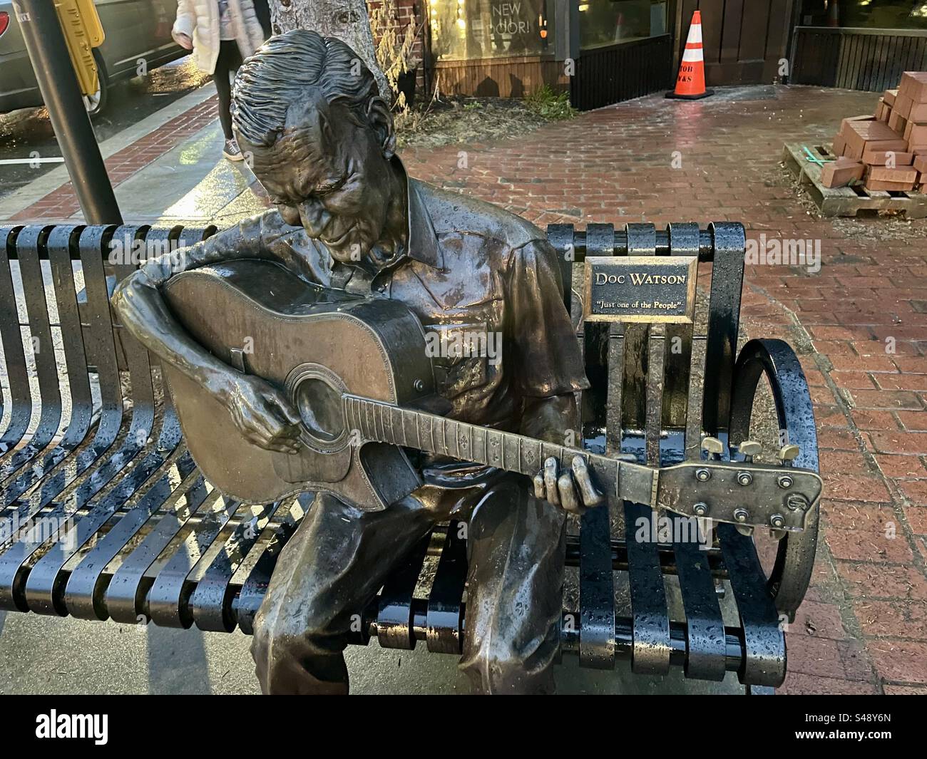 Metal statue of Doc Watson sitting on a bench and playing his guitar on a street corner in Boone, North Carolina. Stock Photo
