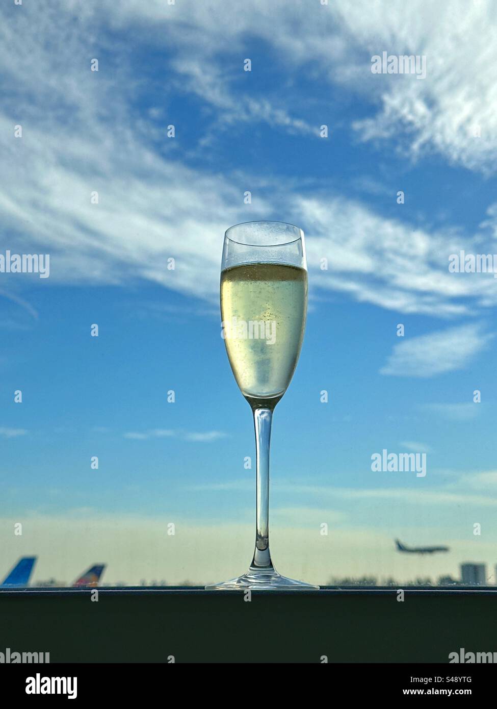 Glass of champagne in the window of an airport lounge. No people. Stock Photo