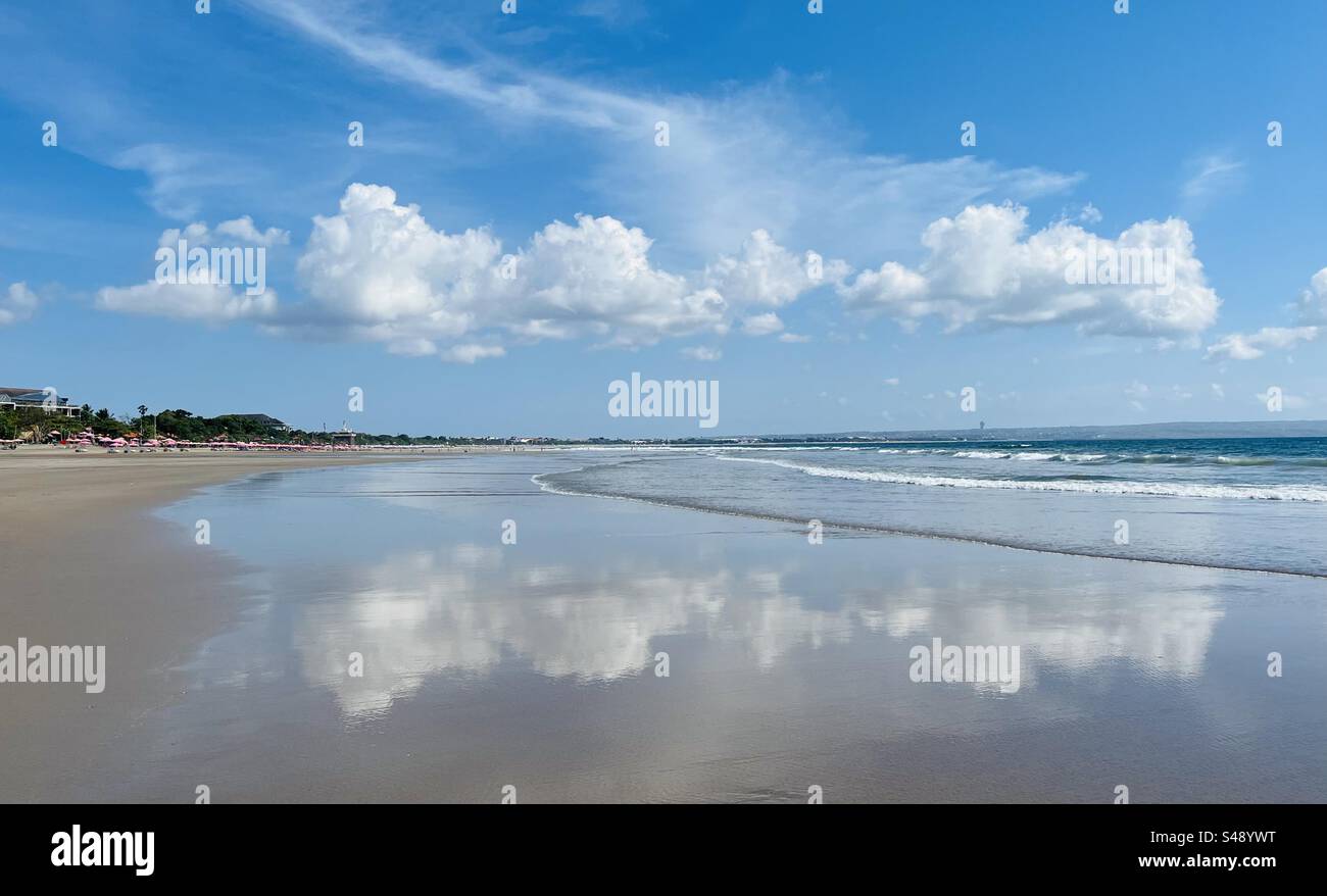 Clouds reflecting in the shallow water of the sea at the beach in Bali Stock Photo