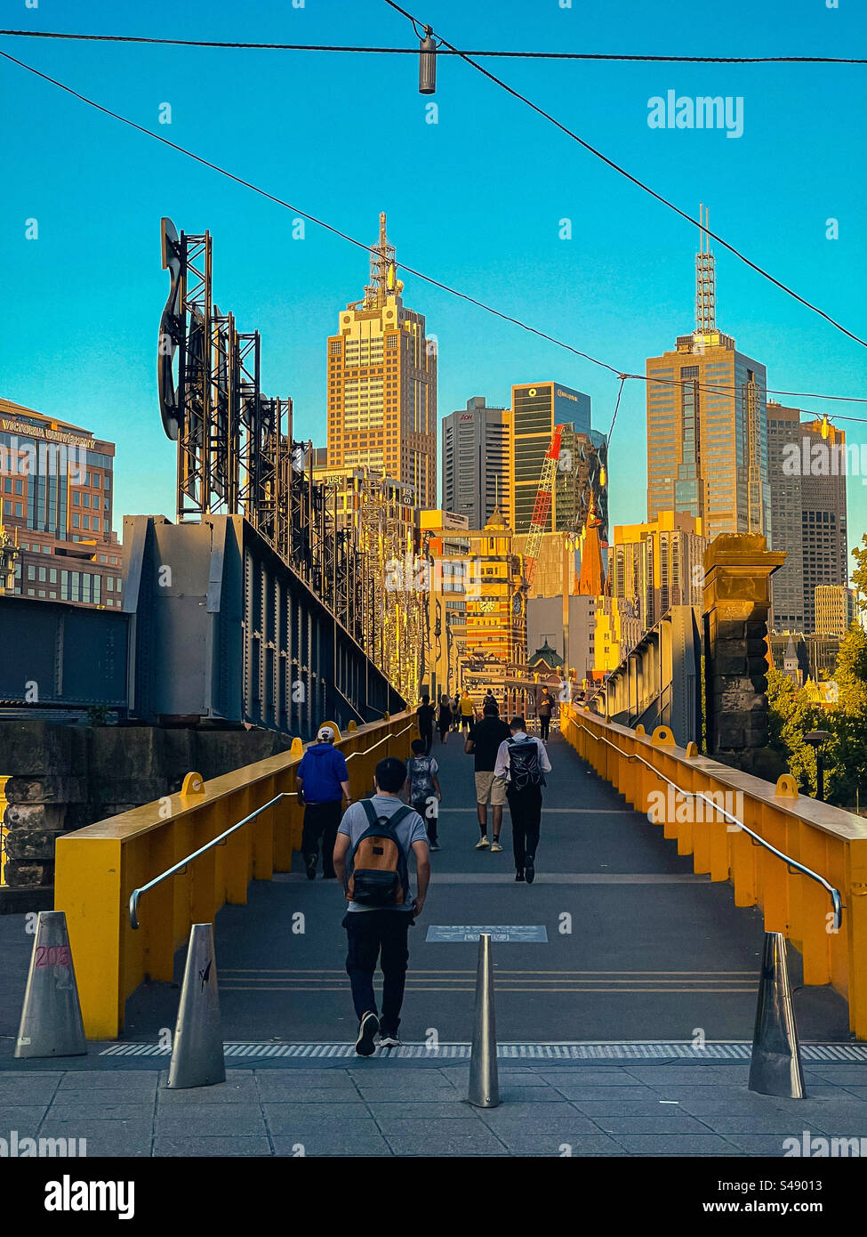 Pedestrians on Sandridge Bridge with buildings, skyscrapers and city skyline at sunset in Melbourne, Australia. - Smartphone Captured Stock Image