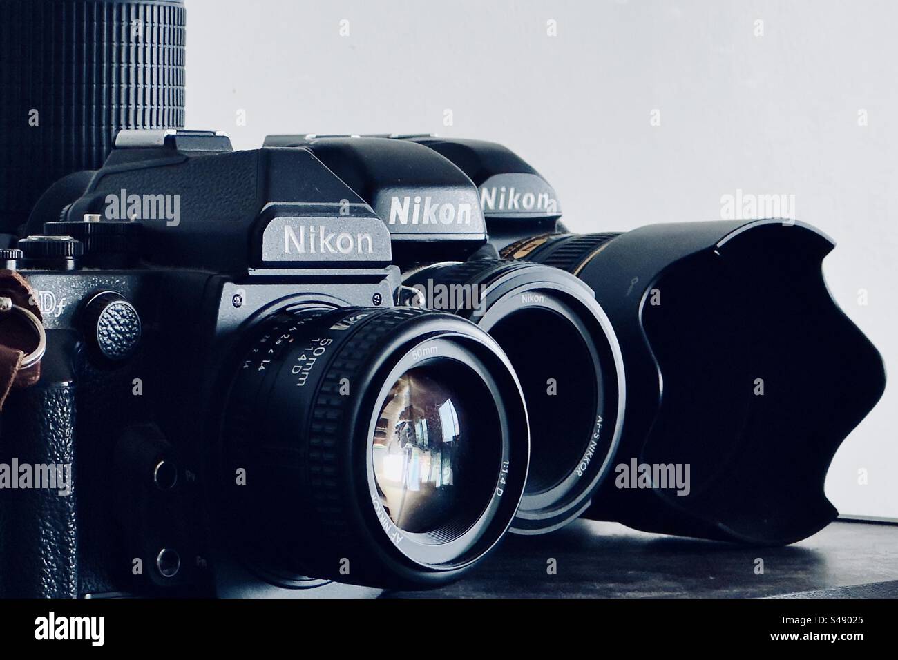 Three Classic Nikon Slr And Dslr Cameras With Three Lenses On A Shelf