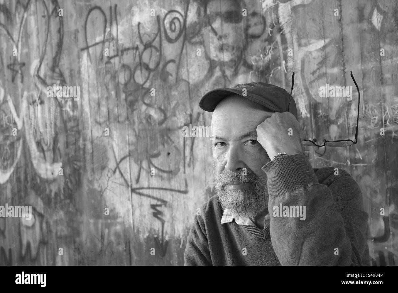 Monochrome portrait of senior man against graffiti wall Stock Photo