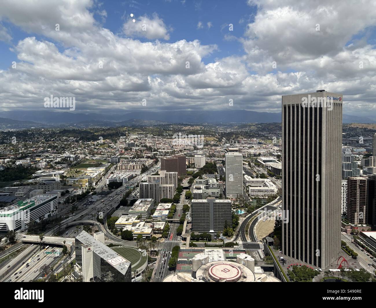 LOS ANGELES, CA, MAY 2023: looking north from tall building in Downtown. Bank of America tower prominent in foreground. China Town and freeways in mid ground. Mountains in distance - Smartphone Captured Stock Image