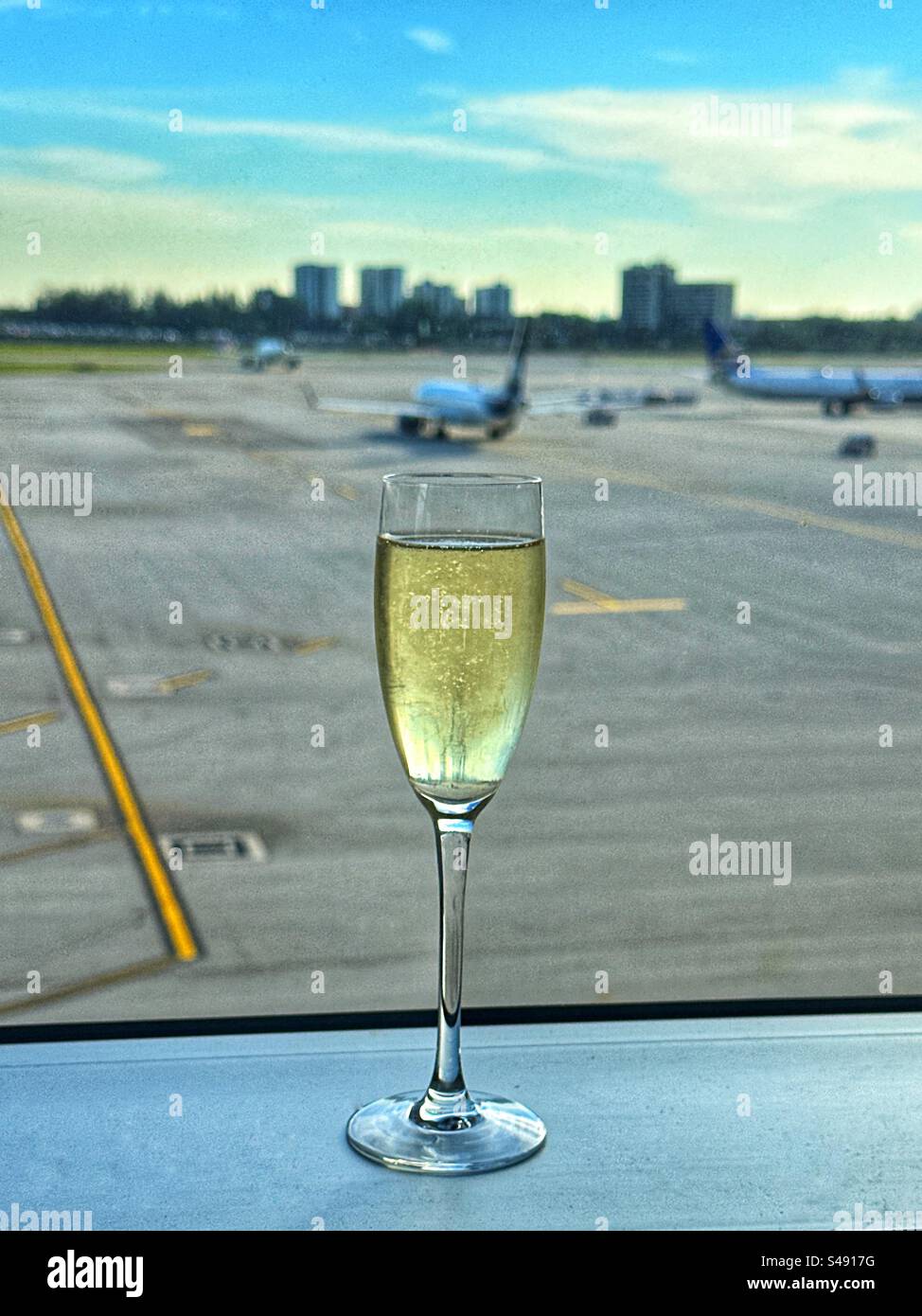 Flute glass of champagne on the window sill of an airport business class lounge. No people. - Smartphone Captured Stock Image