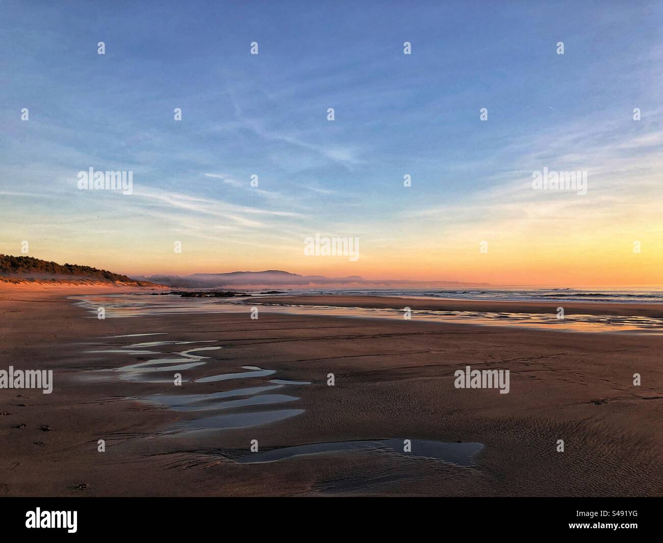 Cabedelo, Viana do Castelo - December 14, 2023: A surfer riding a wave in the Atlantic Ocean under a clear blue sky at sunset - Smartphone Captured Stock Image