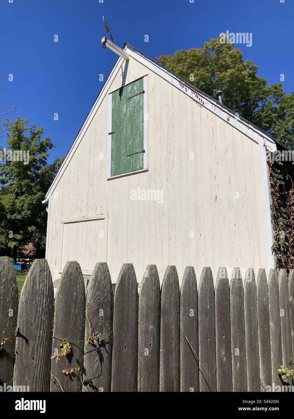 Small barn with green door on second floor in Clinton, Connecticut, USA. Wooden fence in front of the structure. - Smartphone Captured Stock Image