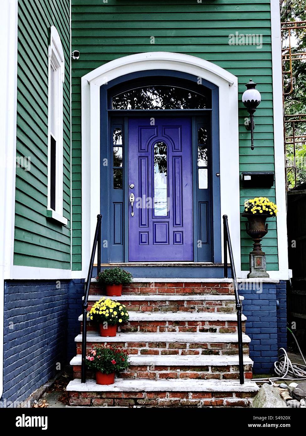 Green house with purple door in New London, Connecticut, USA. Chrysanthemum flowers near entrance to home. - Smartphone Captured Stock Image