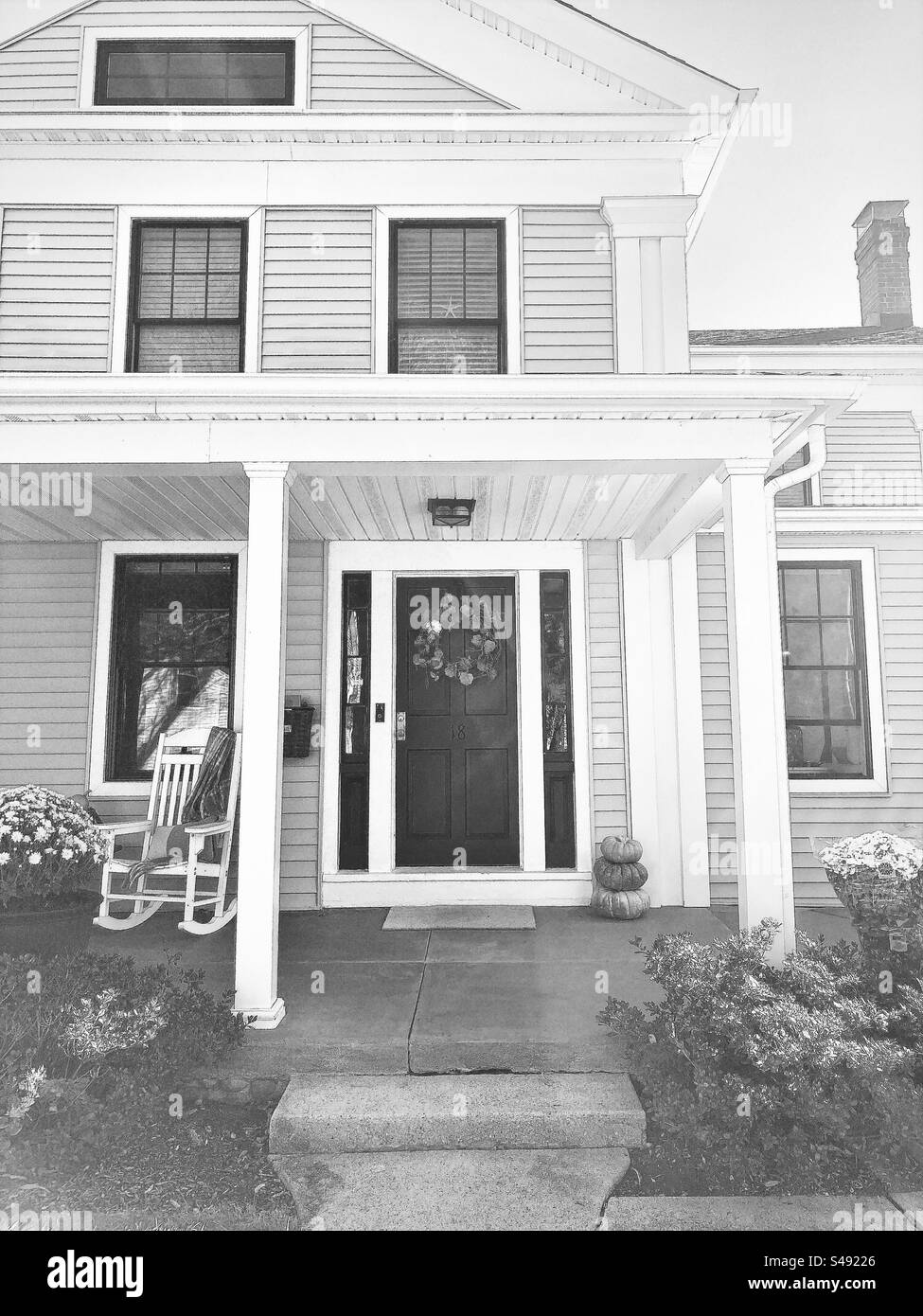 Front portion of house in Clinton, Connecticut, USA.  Porch with rocking chair.  Black and white filter. Stock Photo