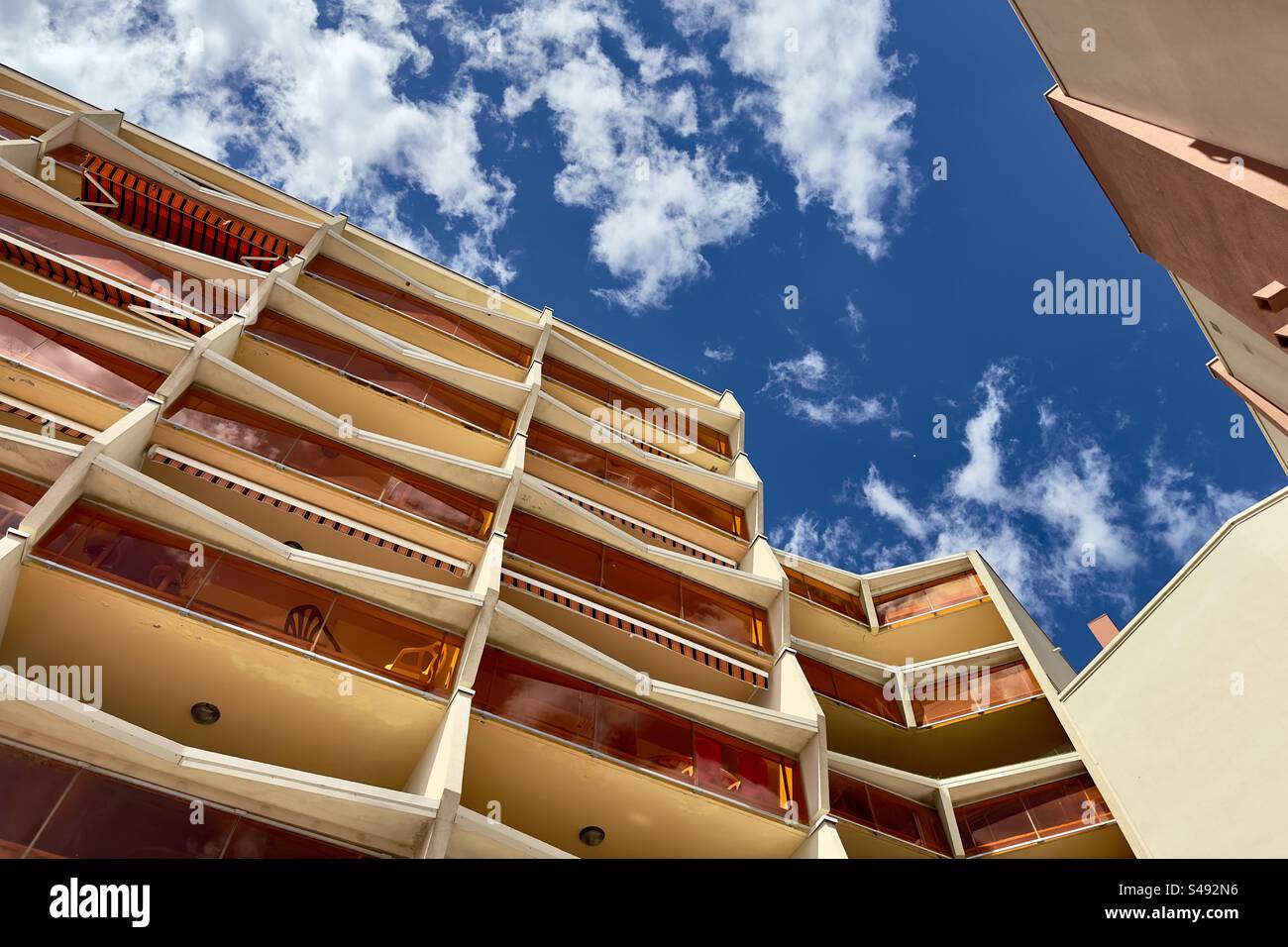 Contrasty landscape photo of the sky and clouds between orange buildings in Palavas, Occitanie, France. - Smartphone Captured Stock Image