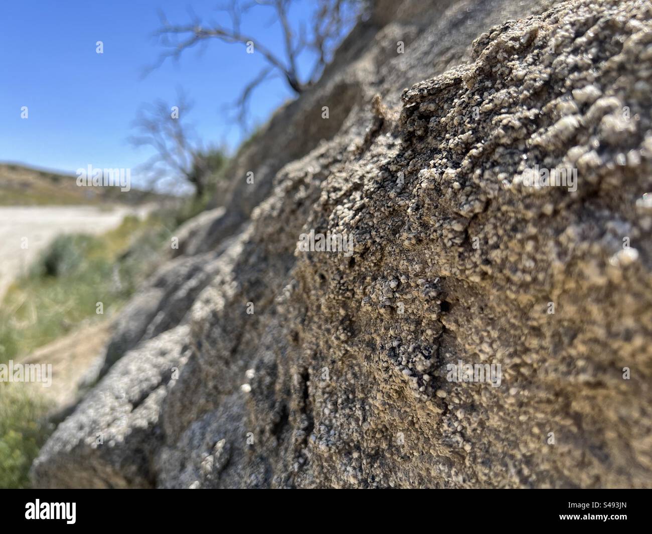 Close view of rocks with soft focus background including partial highway in desert, blue sky overhead, southern California, USA - Smartphone Captured Stock Image Close view of rocks with soft focus background including partial highway in desert, blue sky overhead, southern California, USA - Smartphone Captured Stock Image