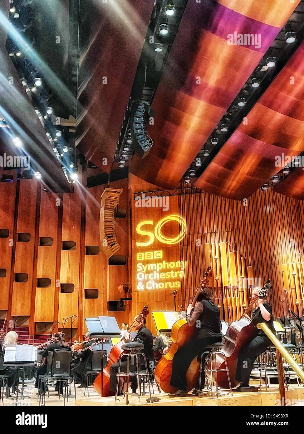 Two double bass players preparing for the concert at the Barbican Hall in London. BBCSO sign projects to the wall. Stock Photo