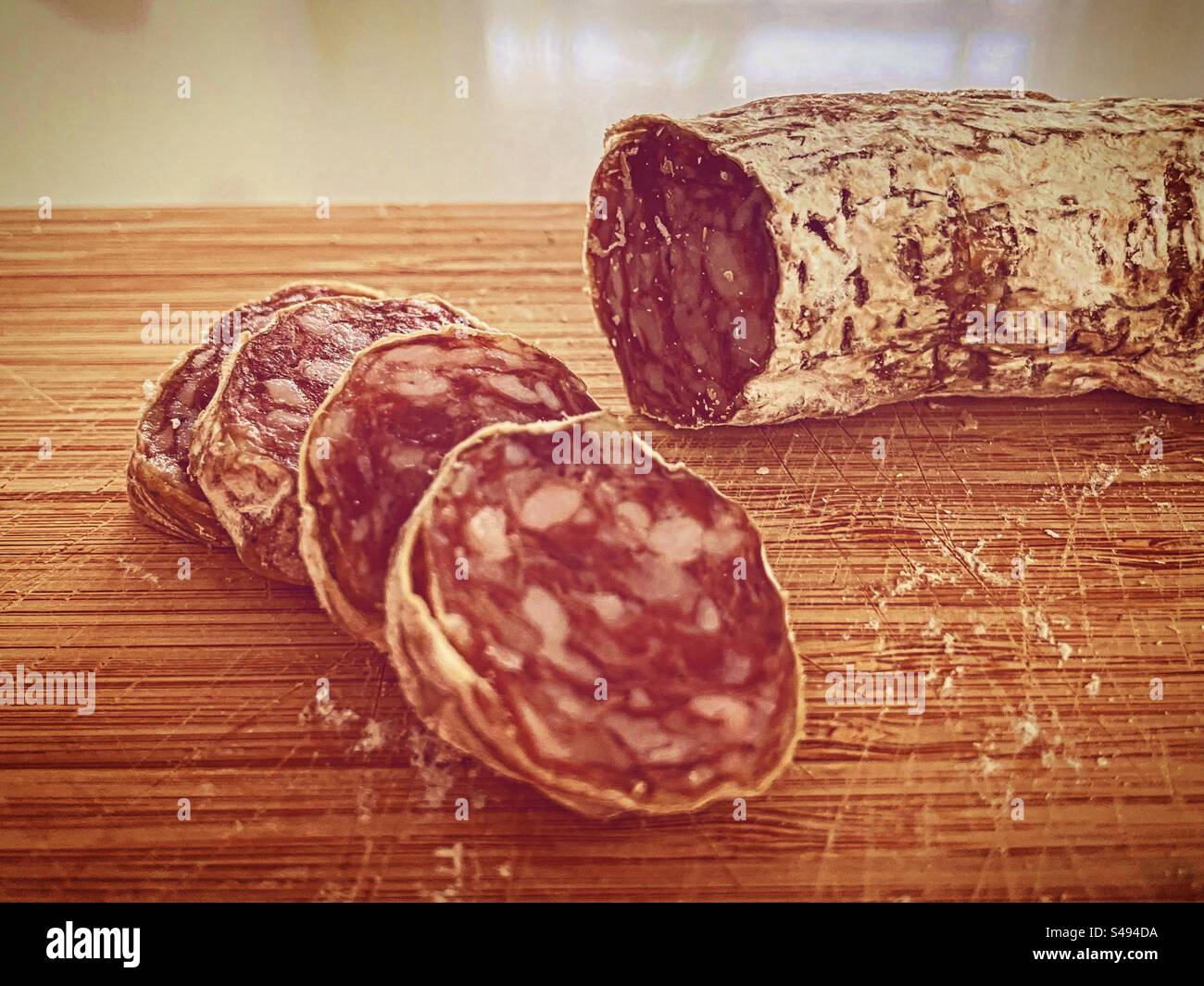 slices of salami dry salted sausage saucisson foid on white wood board in kitchen ready to be eat eaten eating - Smartphone Captured Stock Image