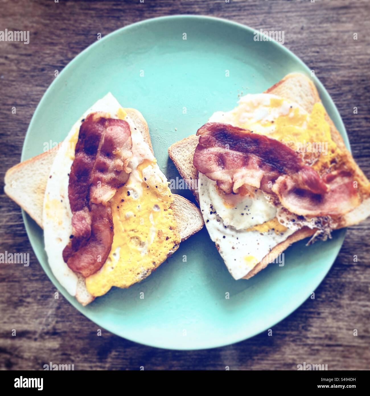 Too view double pork bacon and fried egg toasted bread sandwish for breakfast in a kitchen at home cook cooking like snack for hungry starving - Smartphone Captured Stock Image