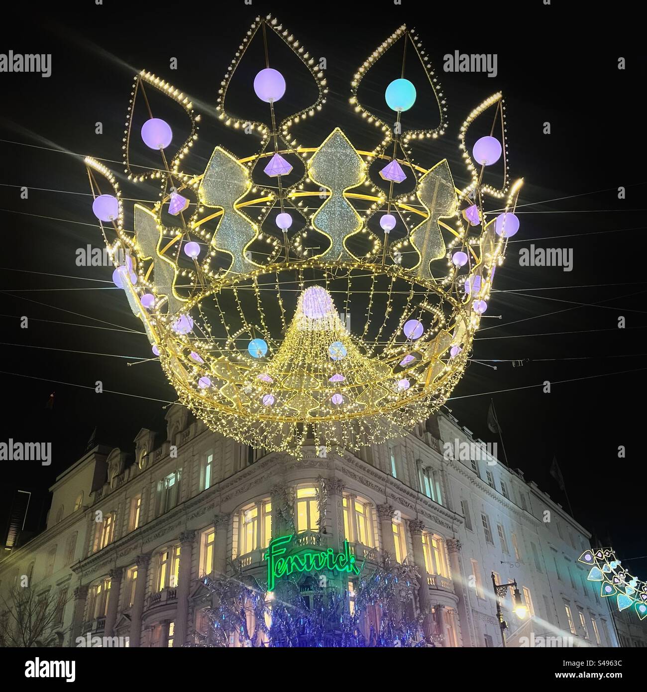 Giant crown street Christmas lights in front of Fenwick Department store in Bond Street in London at night. Colourful winter scene. Stock Photo