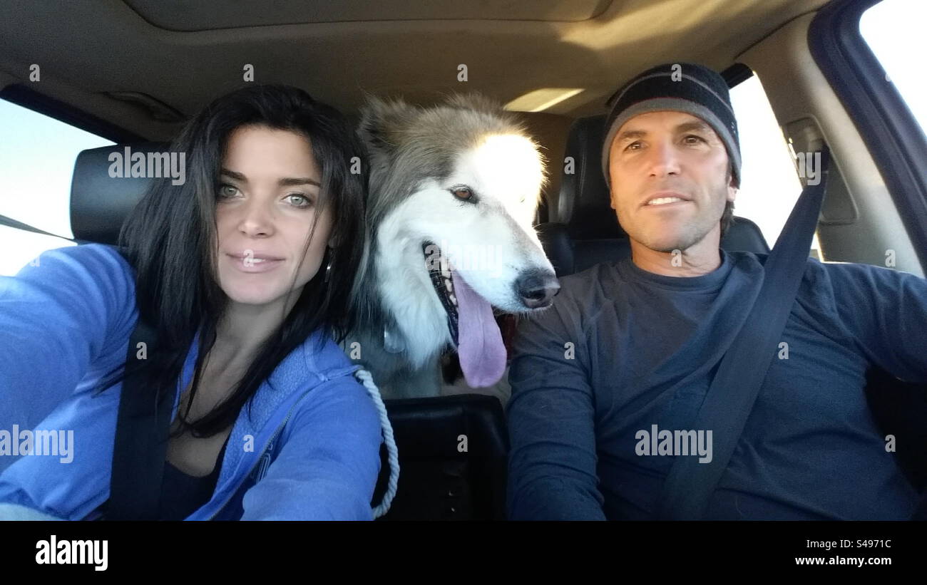 Couple in their car with their dog in the backseat. Stock Photo
