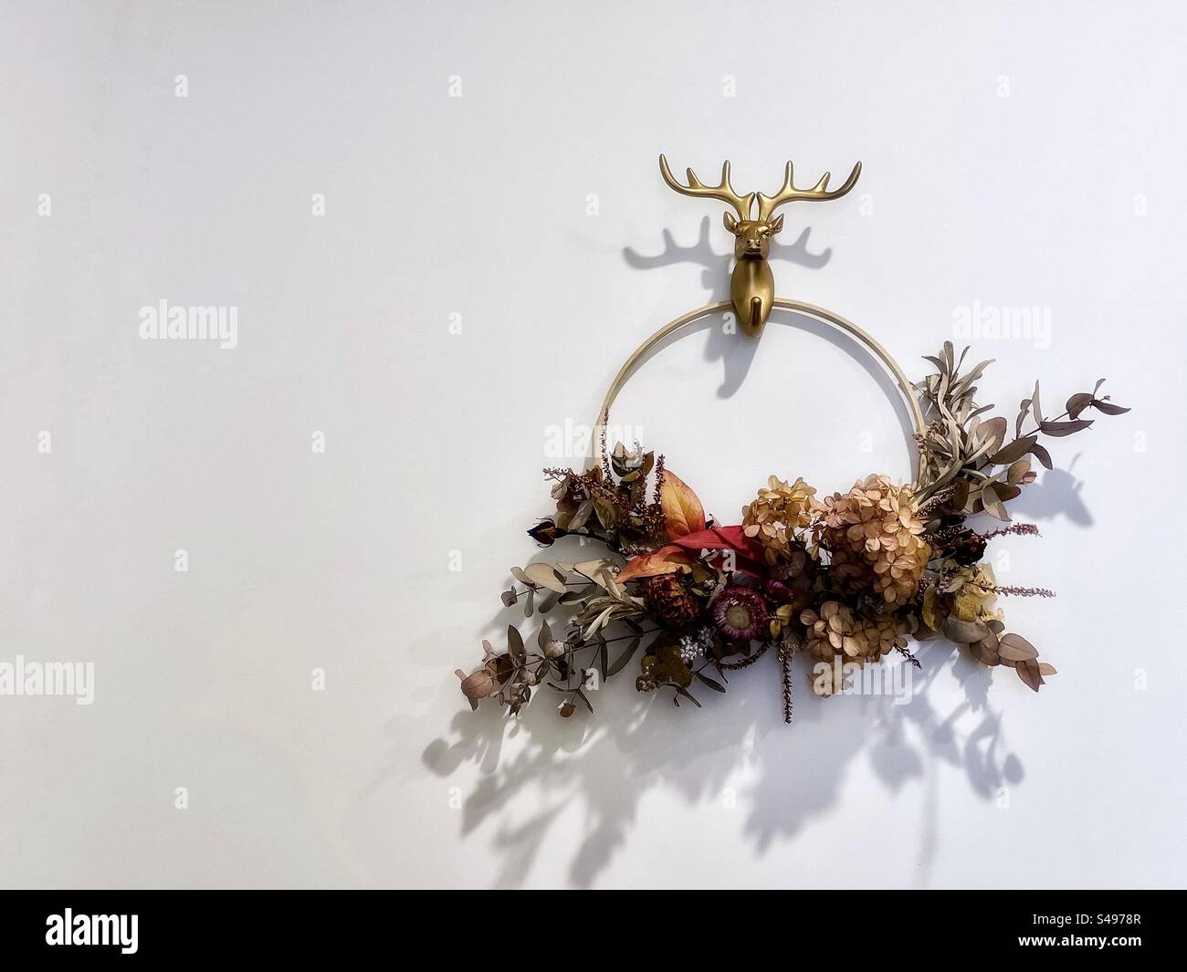 Christmas holiday wreath with dried flowers and foliage on white wall with copy space. - Smartphone Captured Stock Image