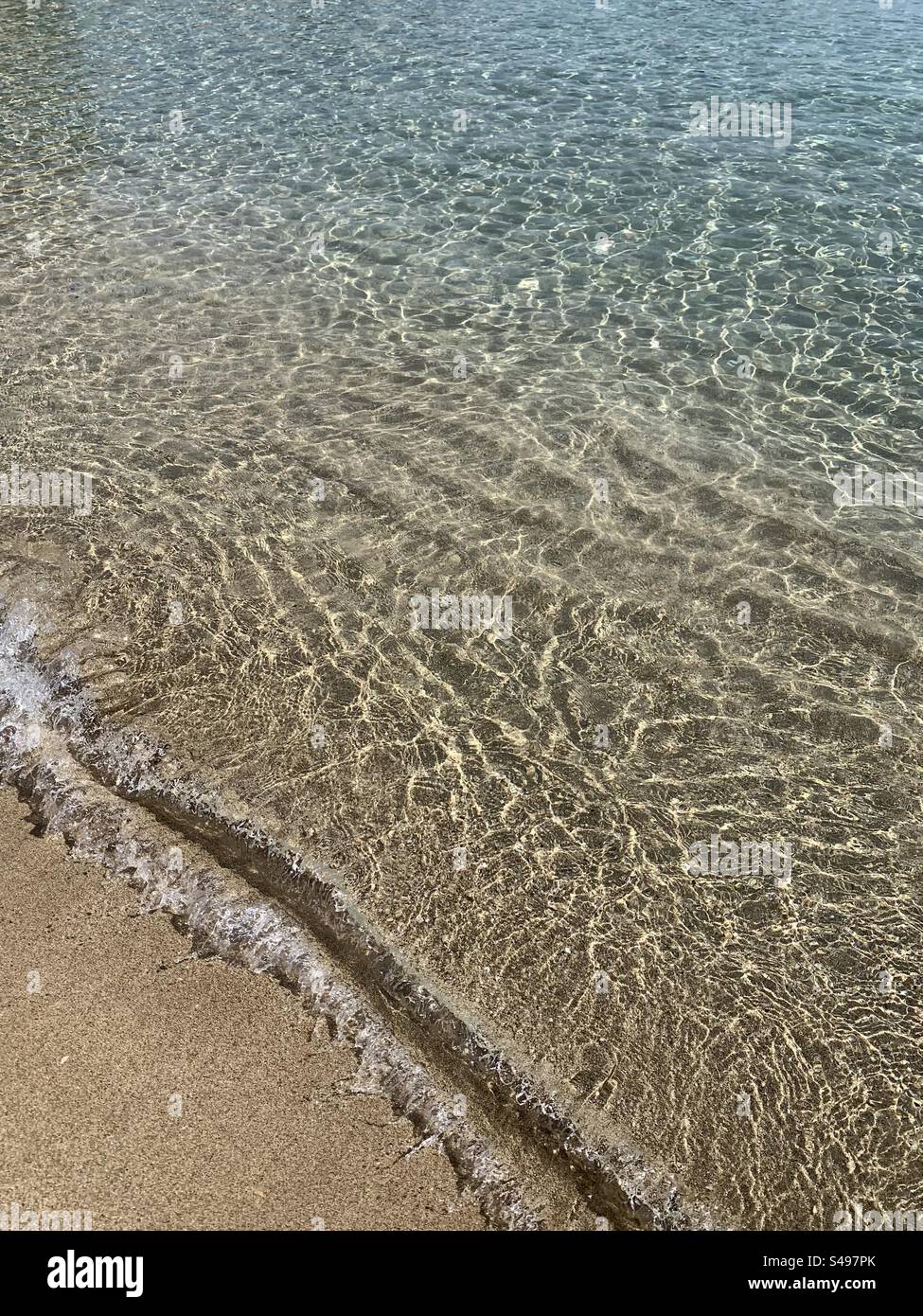 Clear sea lapping up Seashore onto sandy beach - Smartphone Captured Stock Image