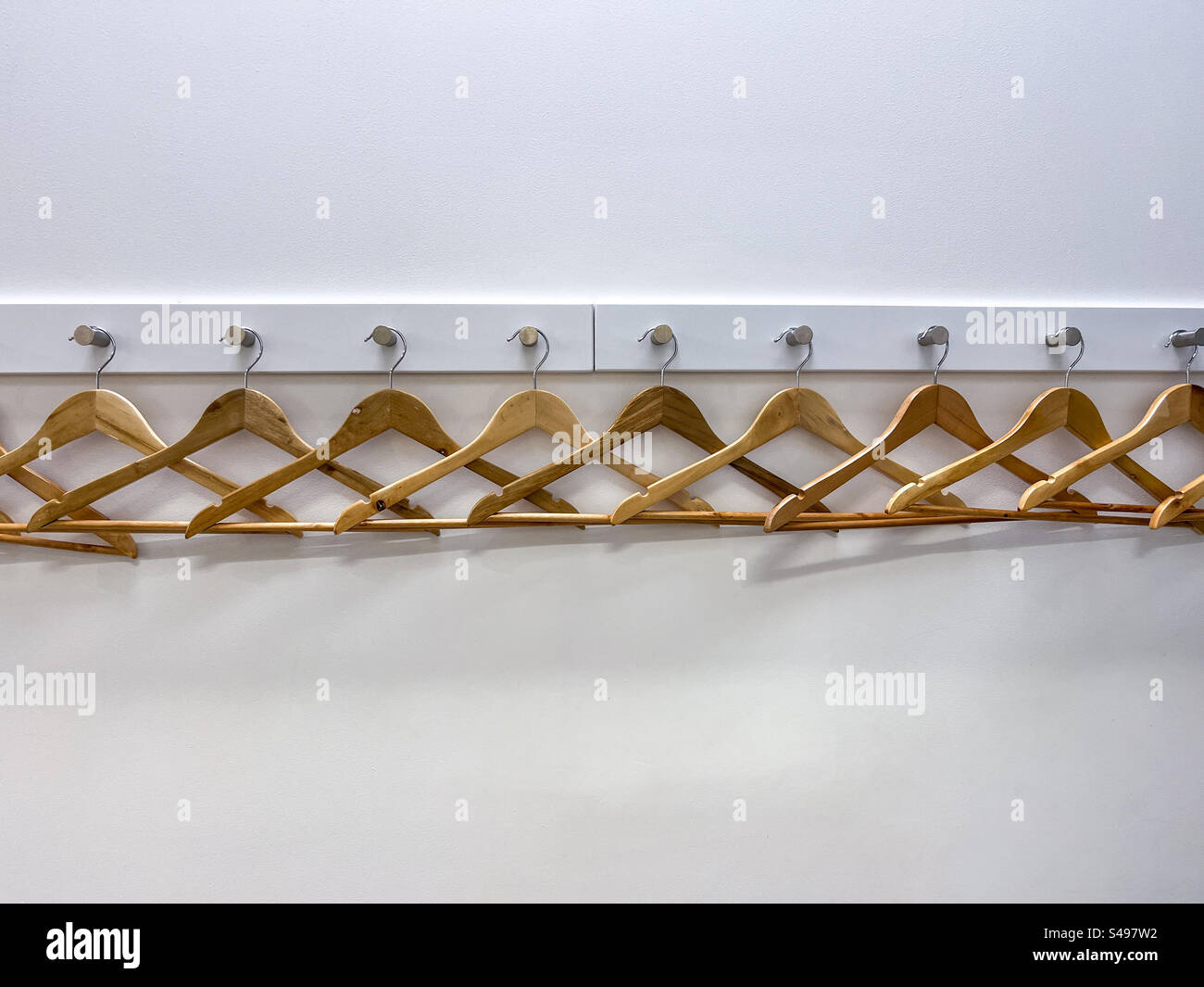 Raw of timber wooden coat hangers against white wall Stock Photo Alamy