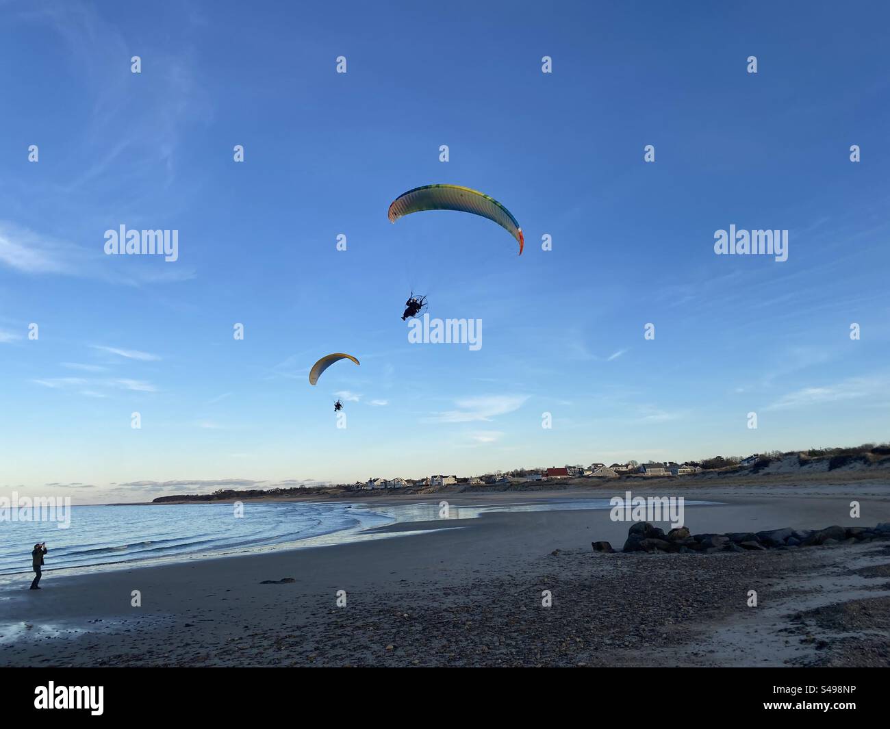 Man photographs a pair of engine powered paragliders over a beach on cape cod mass as sunset approaches. - Smartphone Captured Stock Image