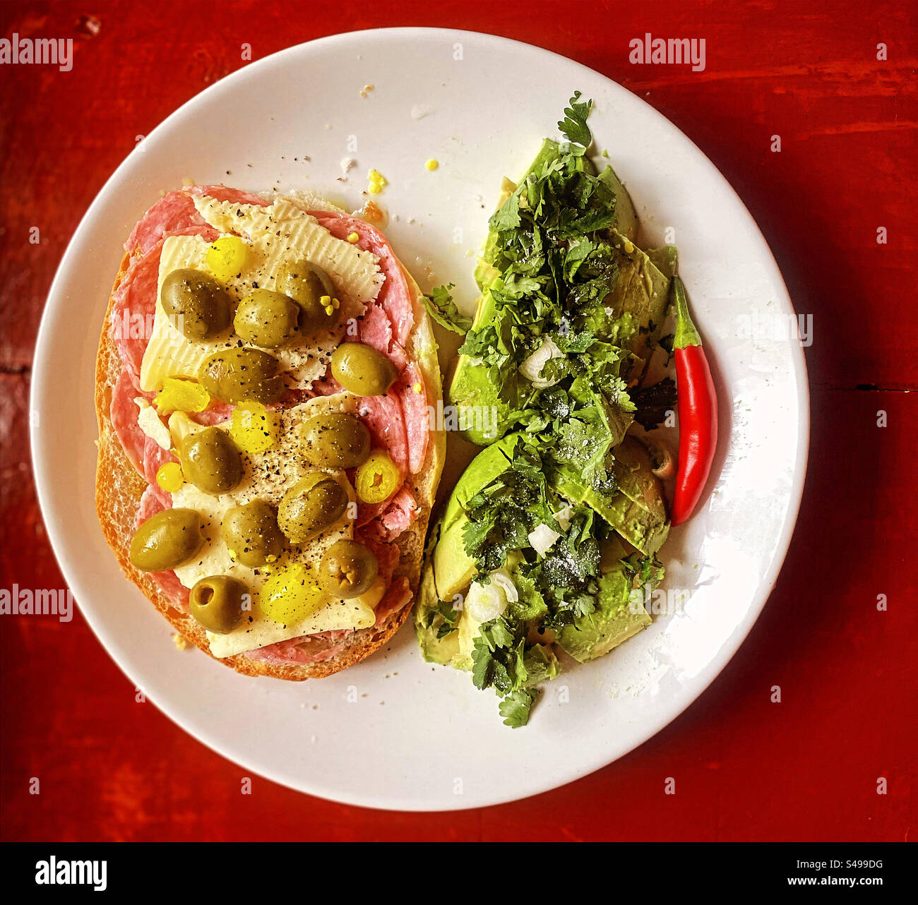 A sandwich of Spanish salchichon sausage, green olives and cheese with avocado salad with coriander and a red hot chilli pepper in. Mexico - Smartphone Captured Stock Image