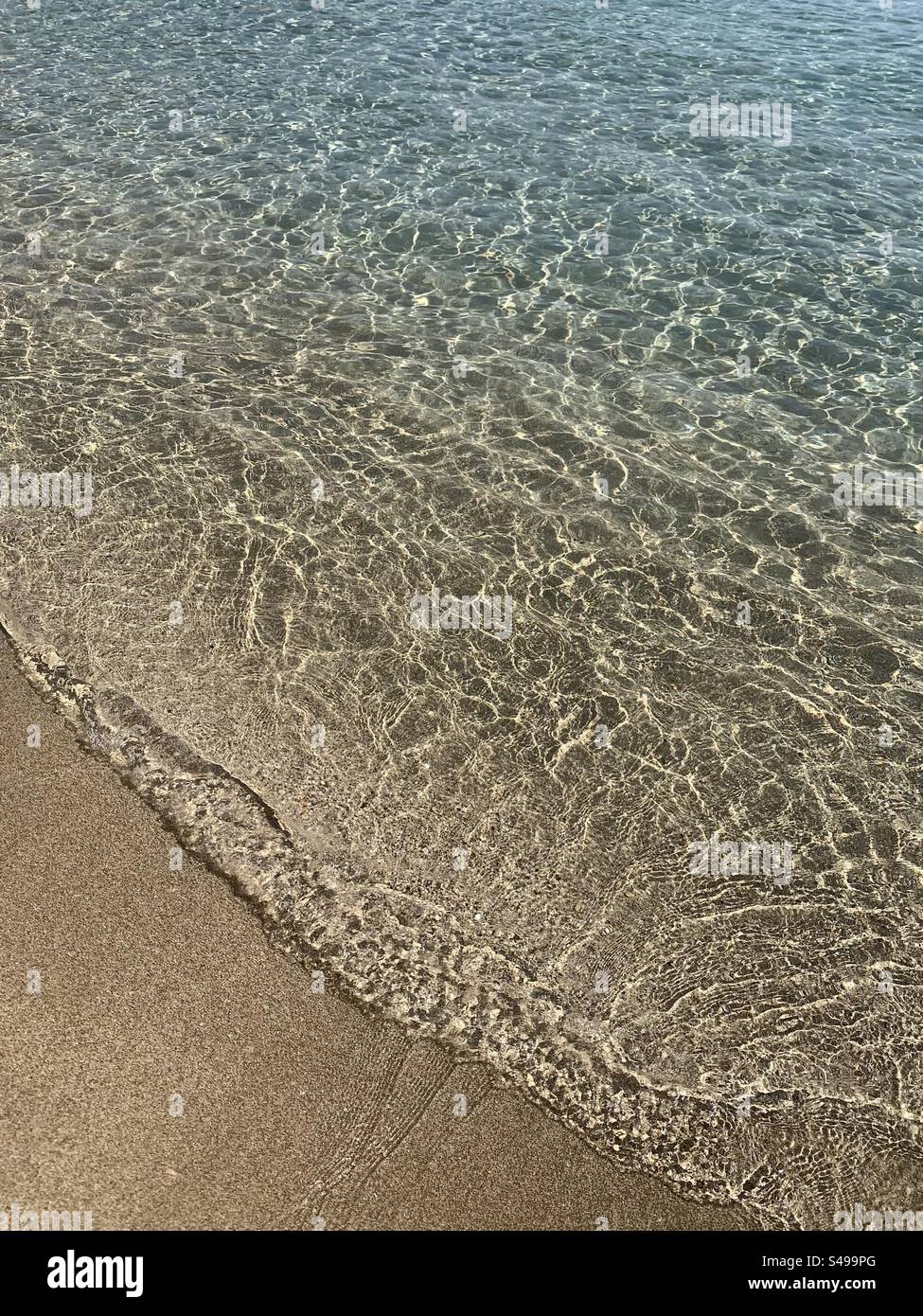 Clear sea lapping onto sandy beach - Smartphone Captured Stock Image
