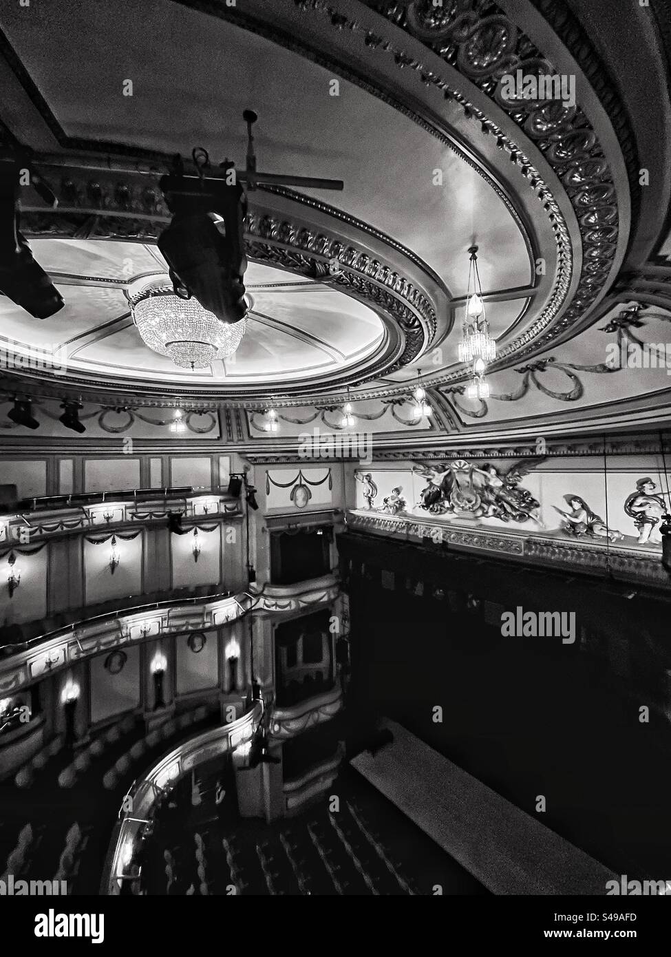 Black and White photograph of the Noël Coward Theatre in London shows stage and ceiling with boxes and tiered seating including stalls. Gilt decoration above the stage. - Smartphone Captured Stock Image