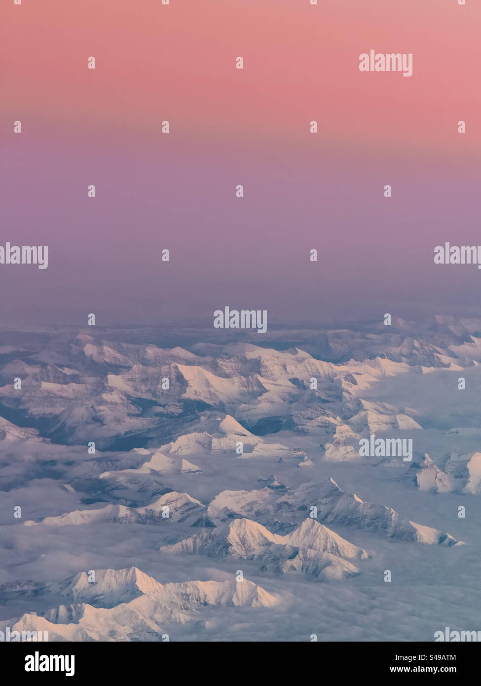 Areal view from a plane of snow covered mountains during sunset - Smartphone Captured Stock Image