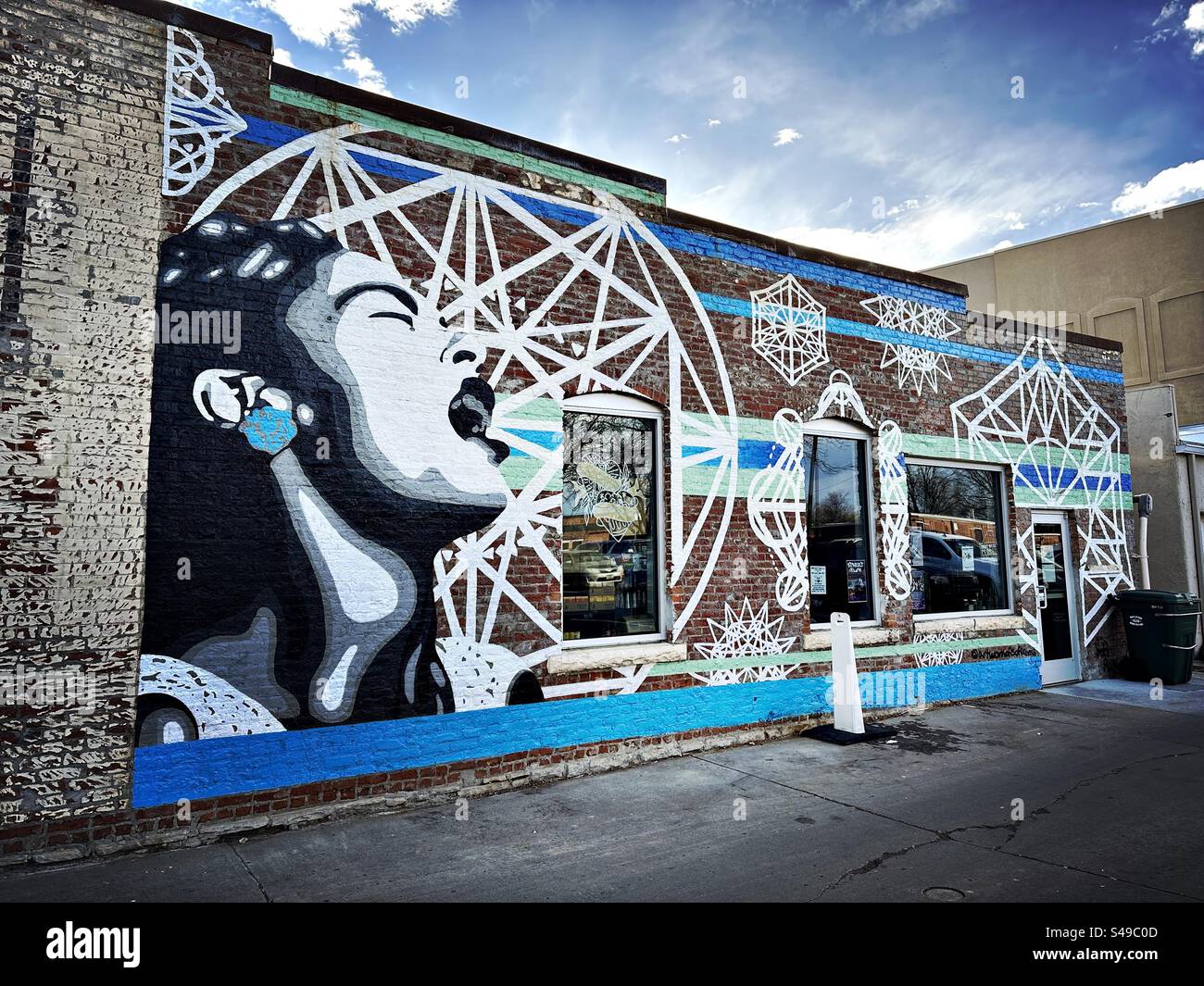 Wall mural of woman in downtown area of Loveland, Colorado, USA.  Door and windows on textured, brick wall. - Smartphone Captured Stock Image