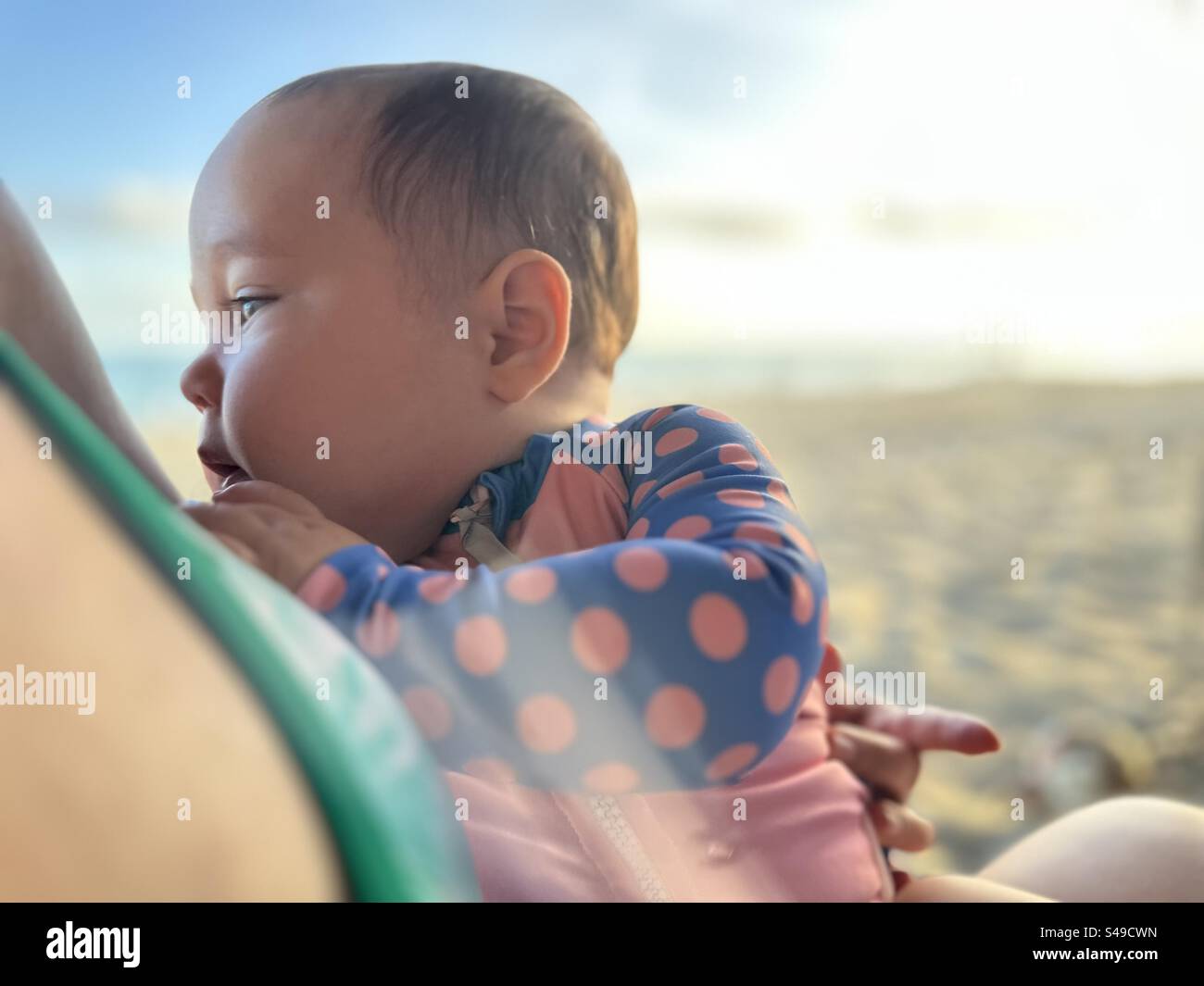 7 Month old baby held by mother in she sand next to the beach - Smartphone Captured Stock Image