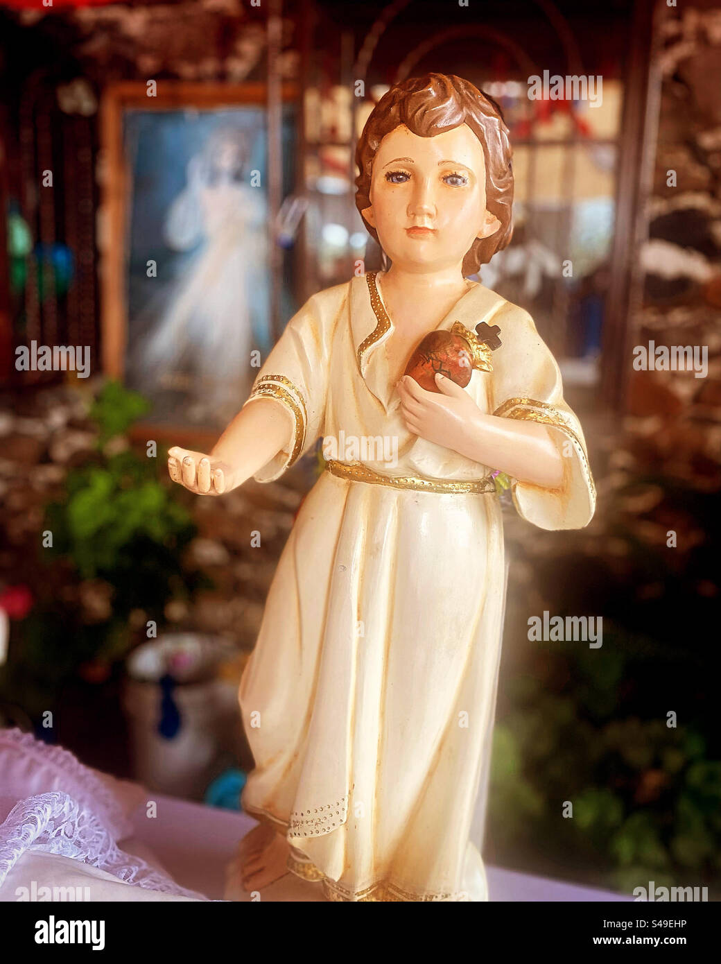 A sculpture of a Baby Jesus holding the Sacred Heart in front of an image of Jesus de la Misericordia in the Capilla de Santiago or Saint James chappel in Colon, Queretaro, Mexico Stock Photo