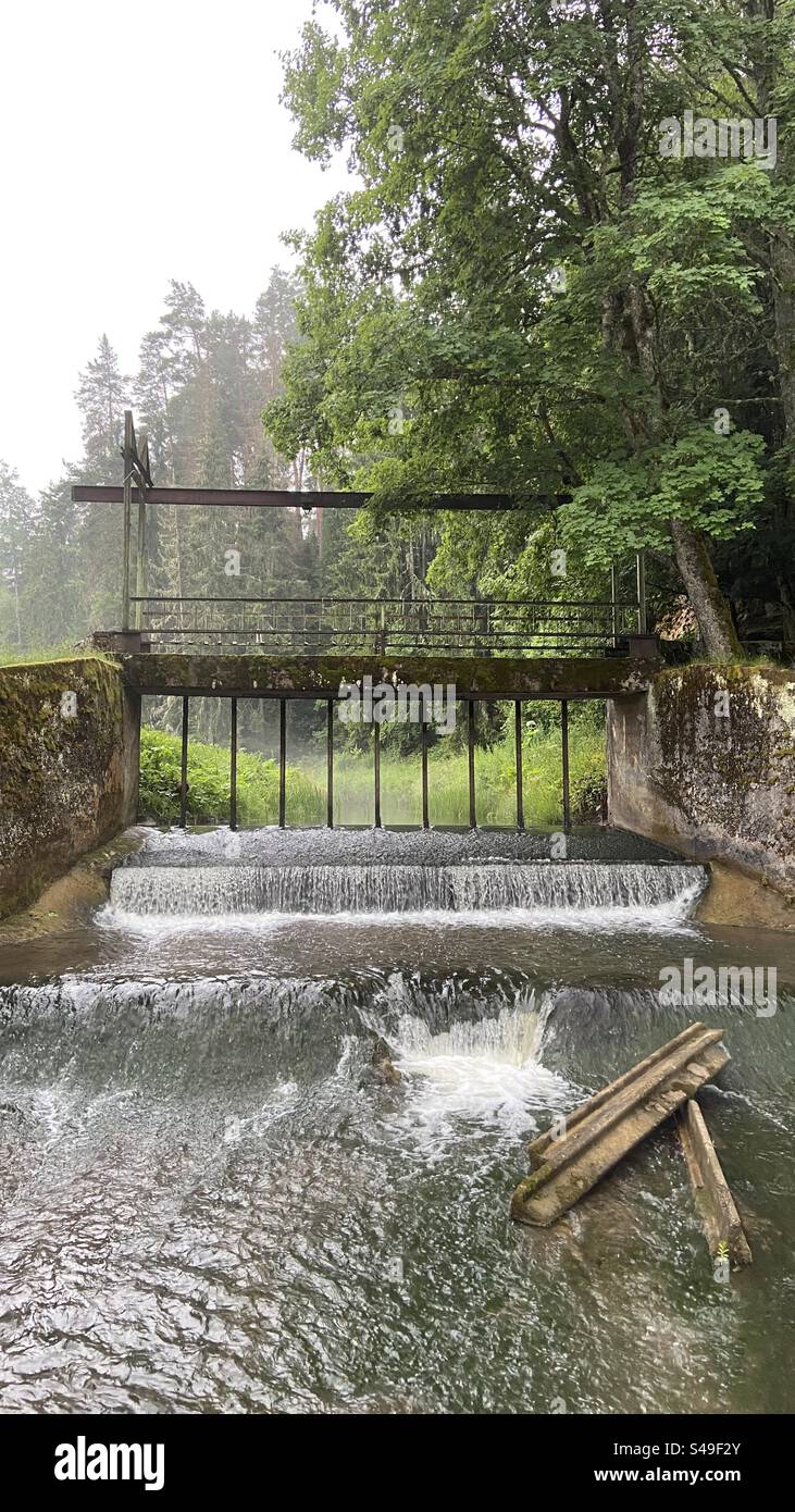 Photo of an old dam near the Vaives Dzirnavas mill in Latvia. Photo taken on a cloudy summer day. Water is flowing down cascades. - Smartphone Captured Stock Image