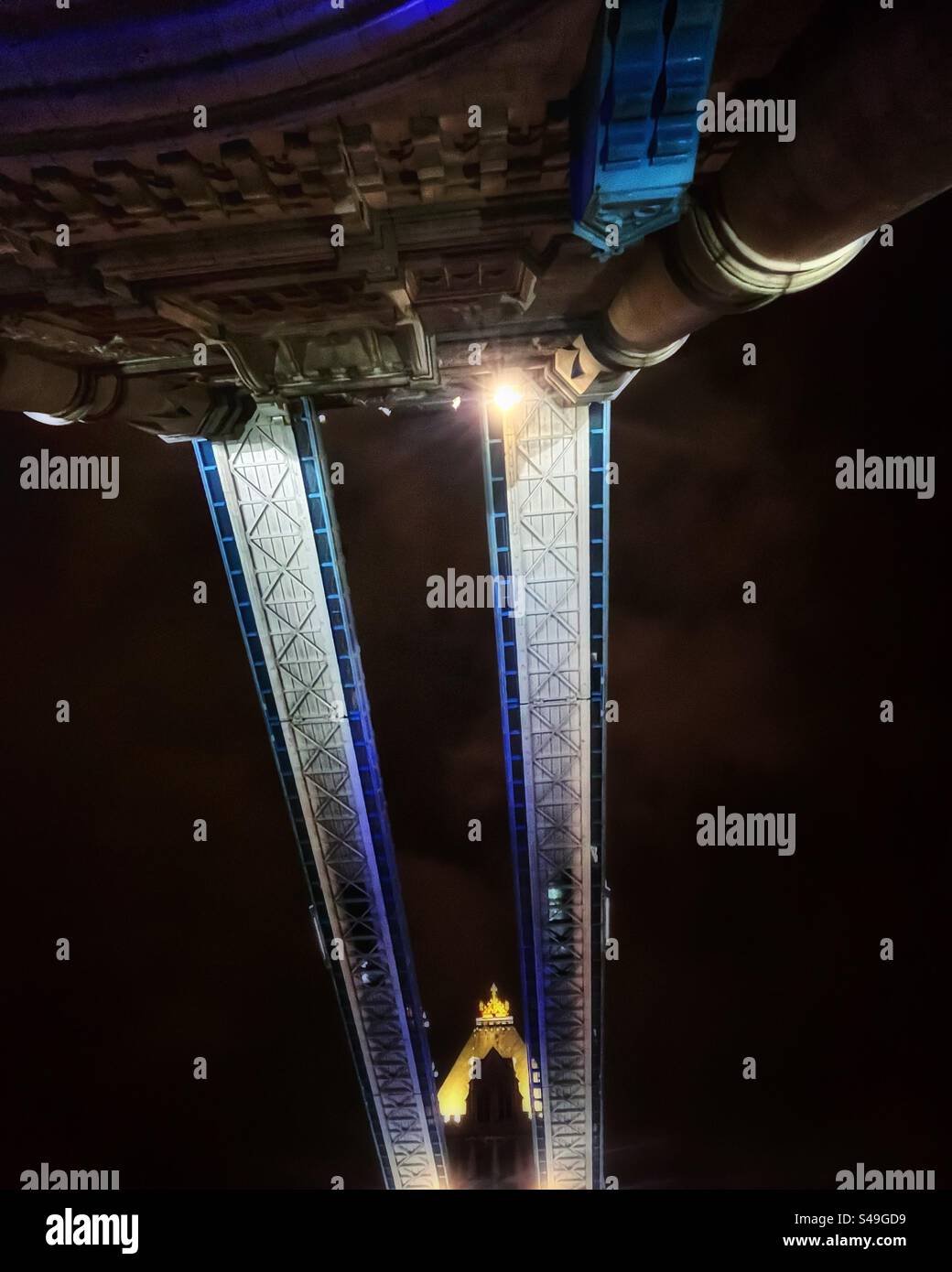 Looking up…at the walkway across the top of Tower Bridge at night - architect Sir Horace Jones and civil engineer Sir John Wolfe Barry. They stand 42 metres above the River Thames. Stock Photo