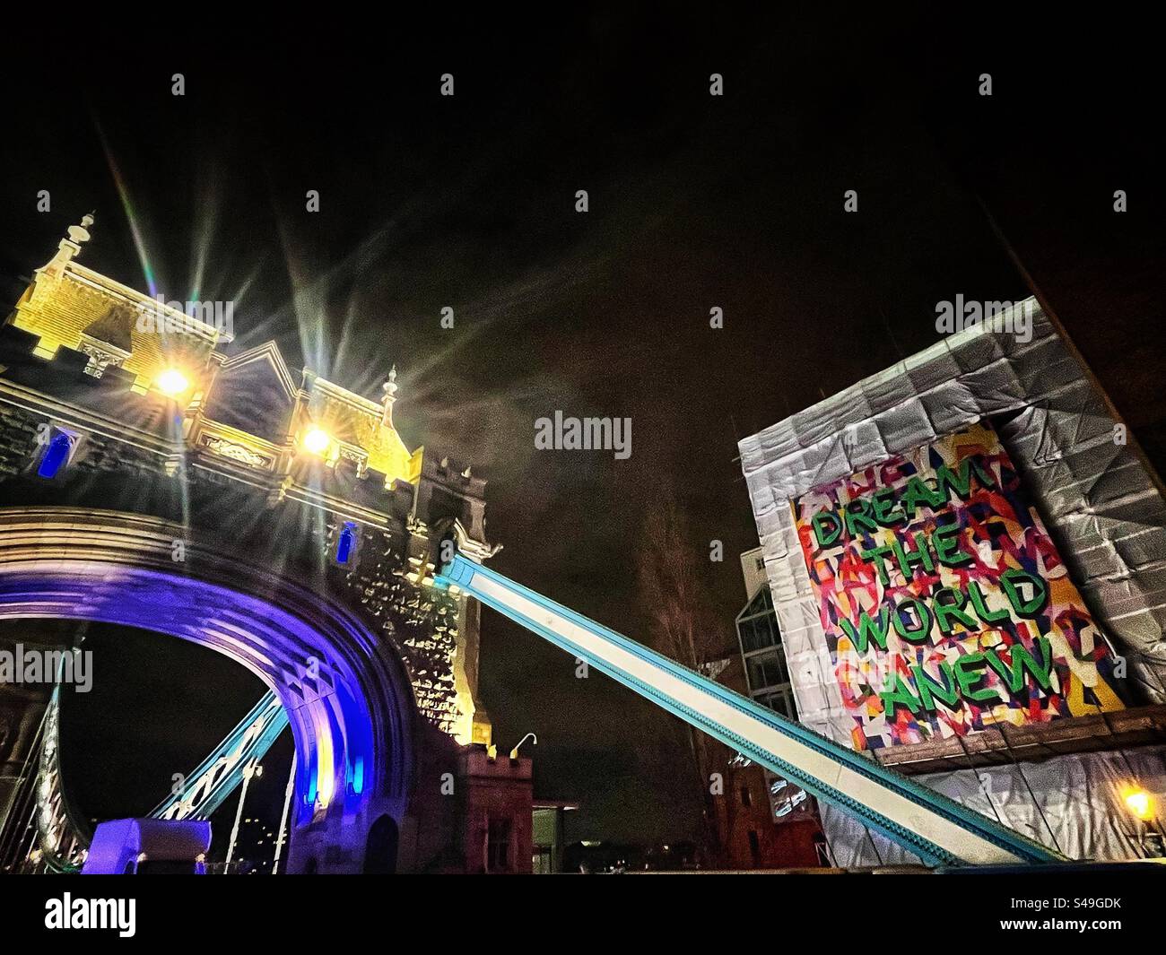 Sign says: “Dream the world anew” and Tower Bridge in London. Seen at night. - Smartphone Captured Stock Image