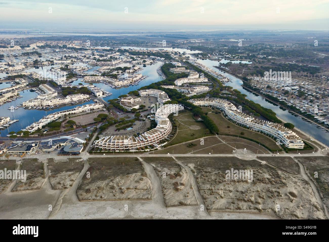 Aerial drone shot of a modern, wave-shaped seafront residence in Port Camargue, Occitanie, France. - Smartphone Captured Stock Image