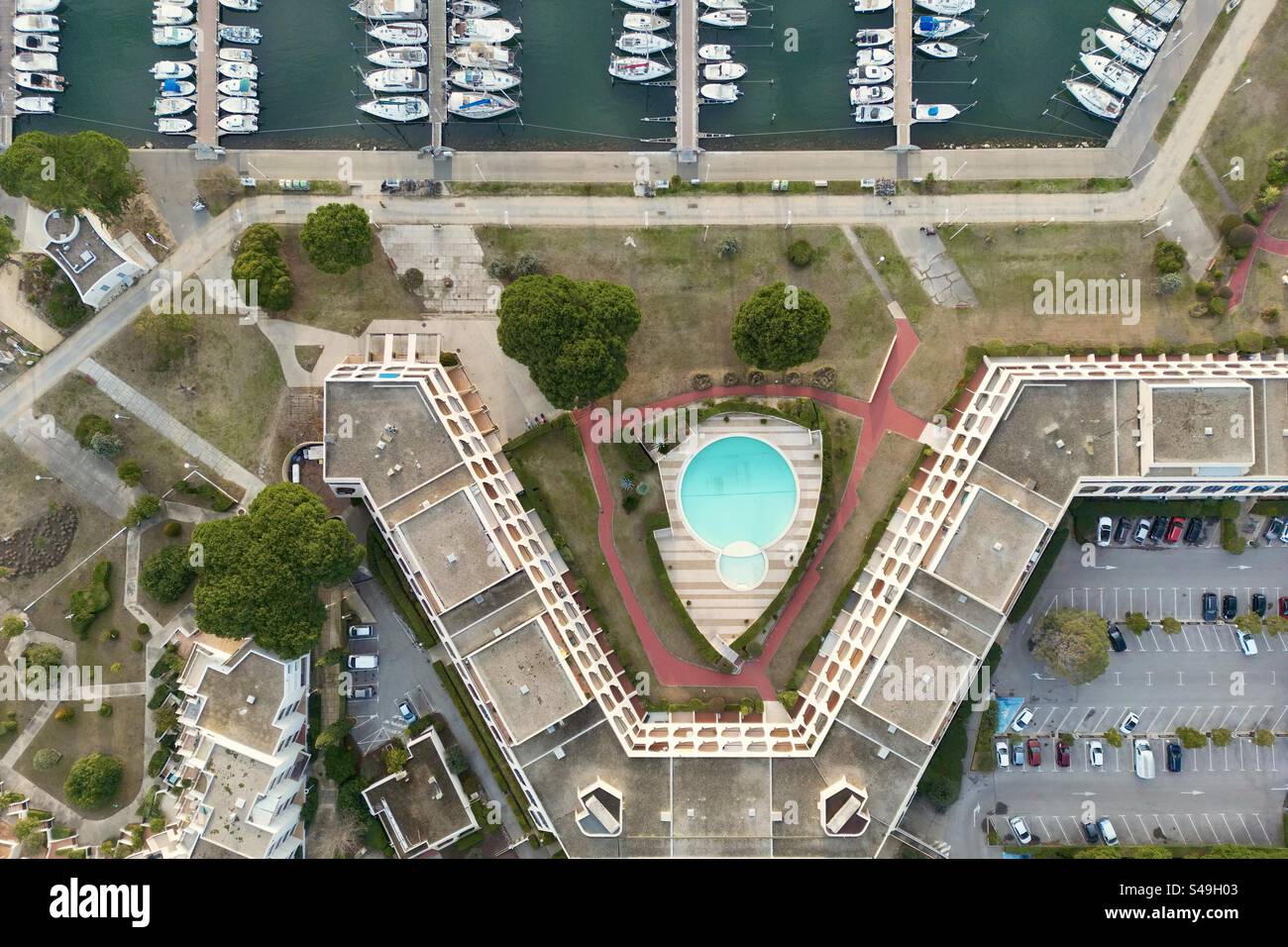 Aerial drone shot of a modern seaside marina residence and swimming pool facing the port in Port Camargue, Occitanie, France. - Smartphone Captured Stock Image