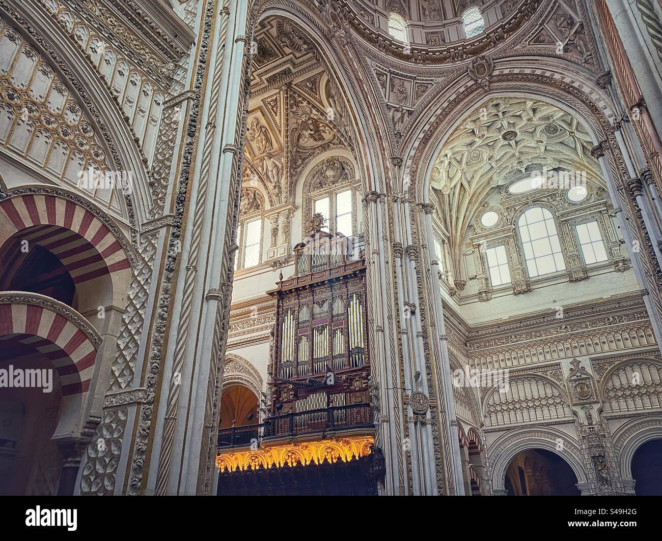Pipe organ among white ornate walls and arches in the Christian part of Mosque-Cathedral in Córdoba, Spain. - Smartphone Captured Stock Image