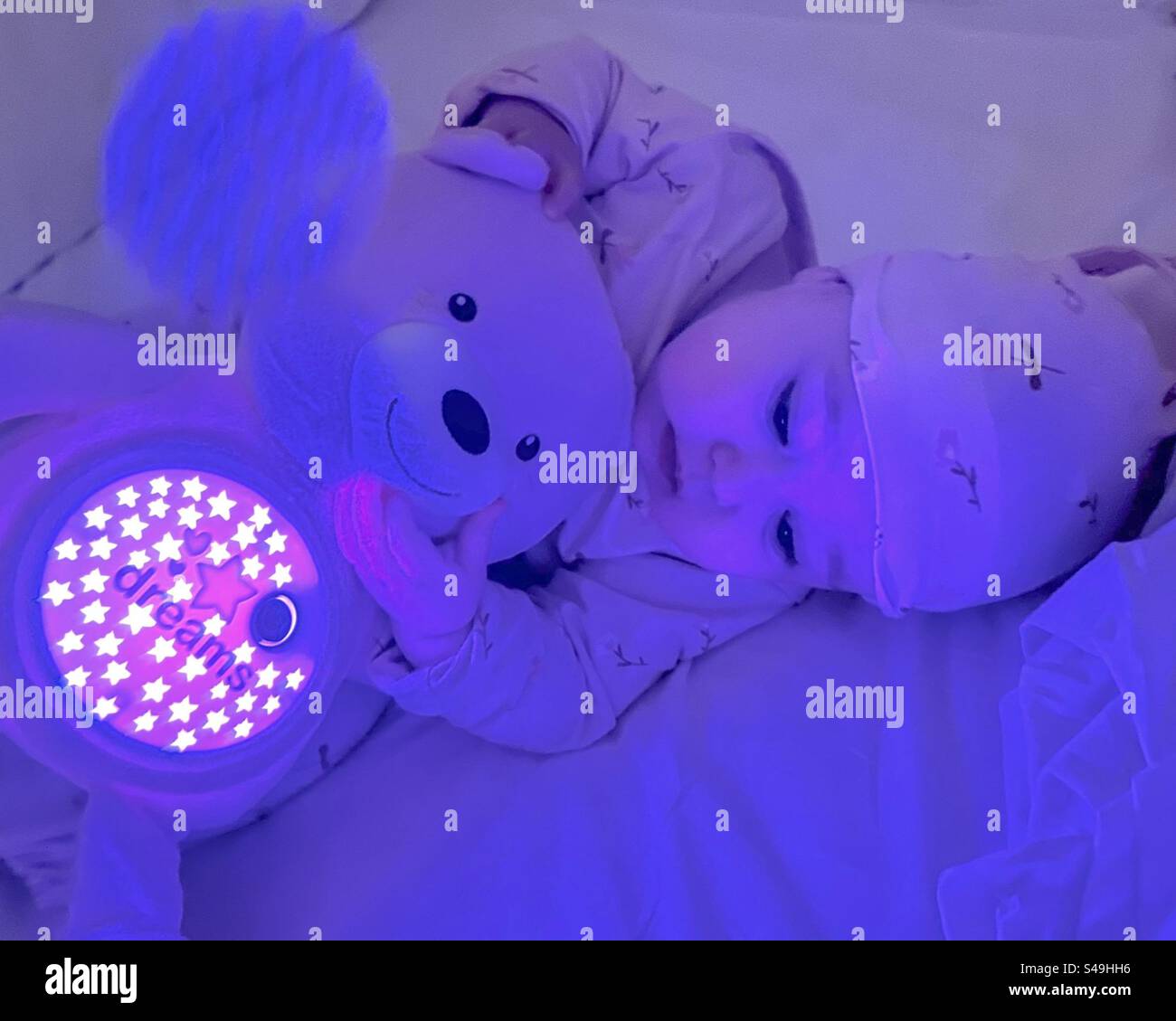 Baby enjoying stuffed toy bear that displays star shapes before bedtime - Smartphone Captured Stock Image