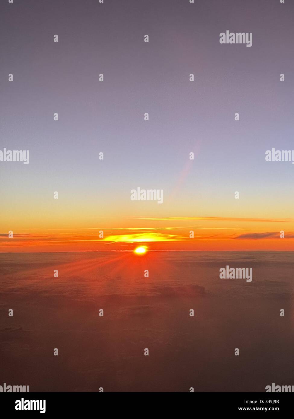 Sunrise above clouds over the Atlantic Ocean on a flight from the Azores to Lisbon. - Smartphone Captured Stock Image