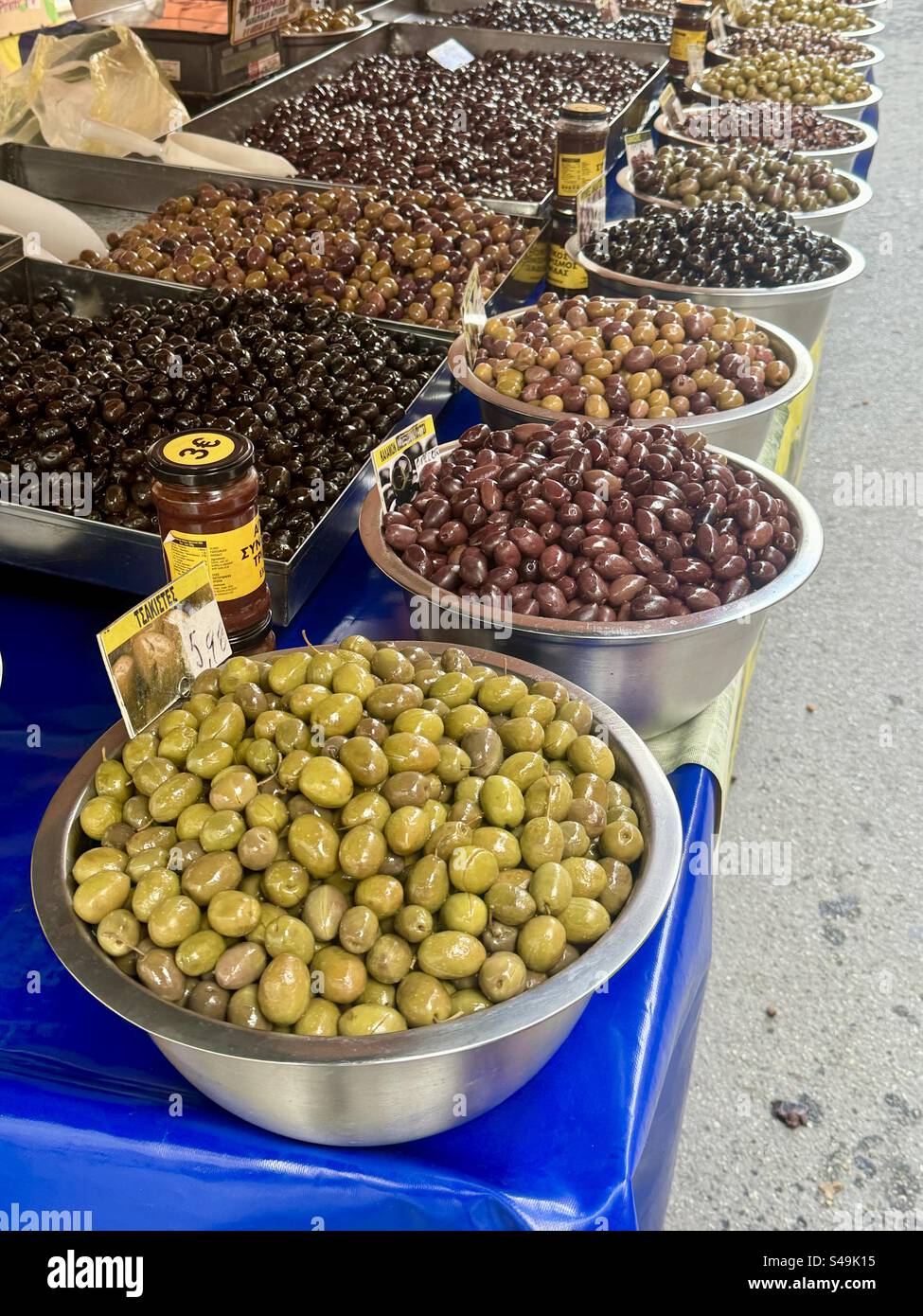 Colorful assortment of green, black, and purple olives on display at a traditional Greek street market. - Smartphone Captured Stock Image