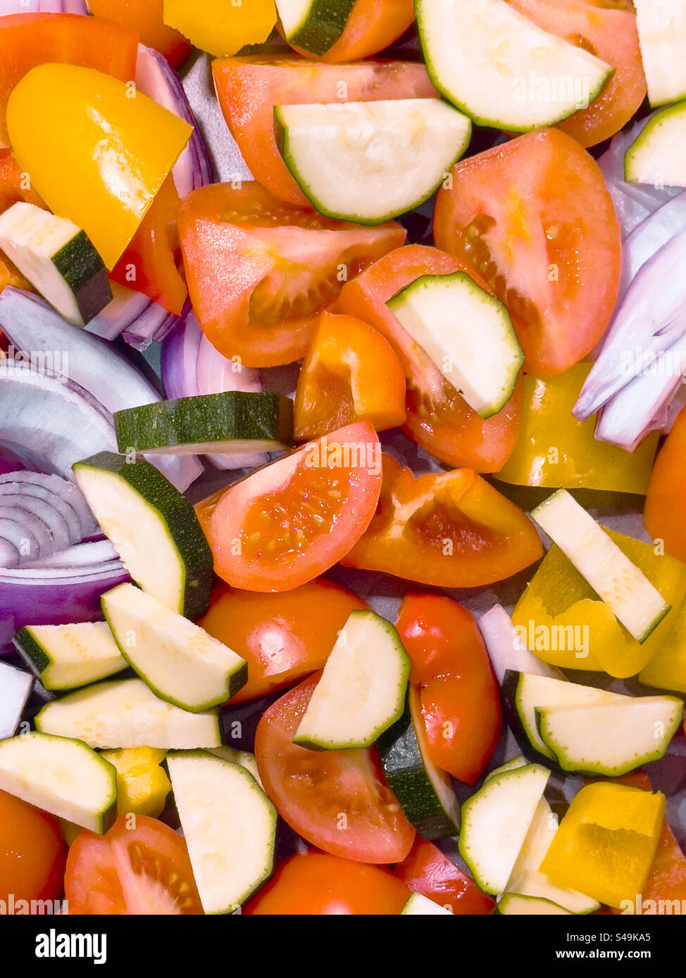 A vibrant medley of tray-bake vegetables, glistening with olive oil and seasoned to perfection, is ready for the oven: Phillip Roberts - Smartphone Captured Stock Image