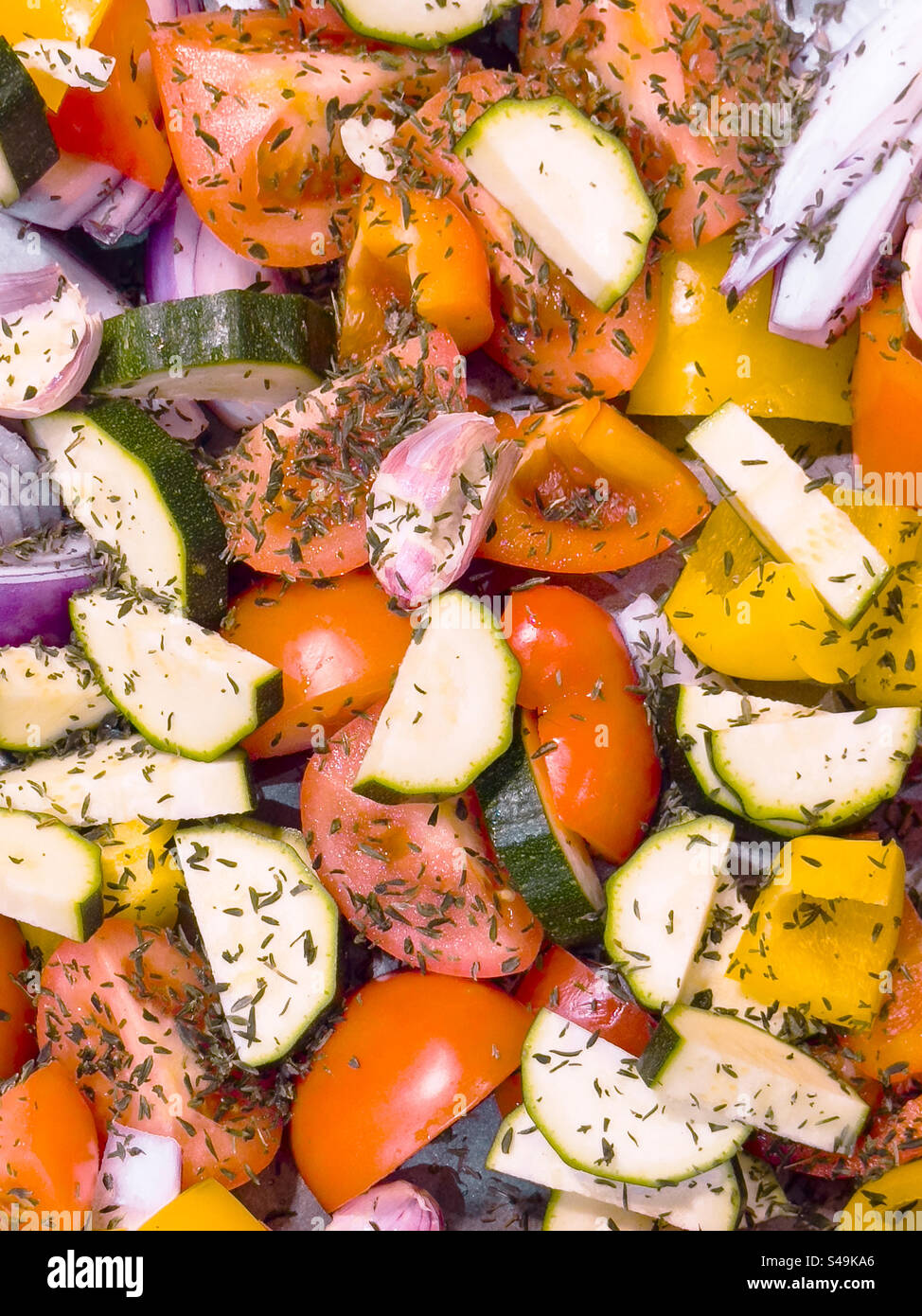 A vibrant medley of tray-bake vegetables, glistening with olive oil and seasoned to perfection, is ready for the oven: Phillip Roberts - Smartphone Captured Stock Image