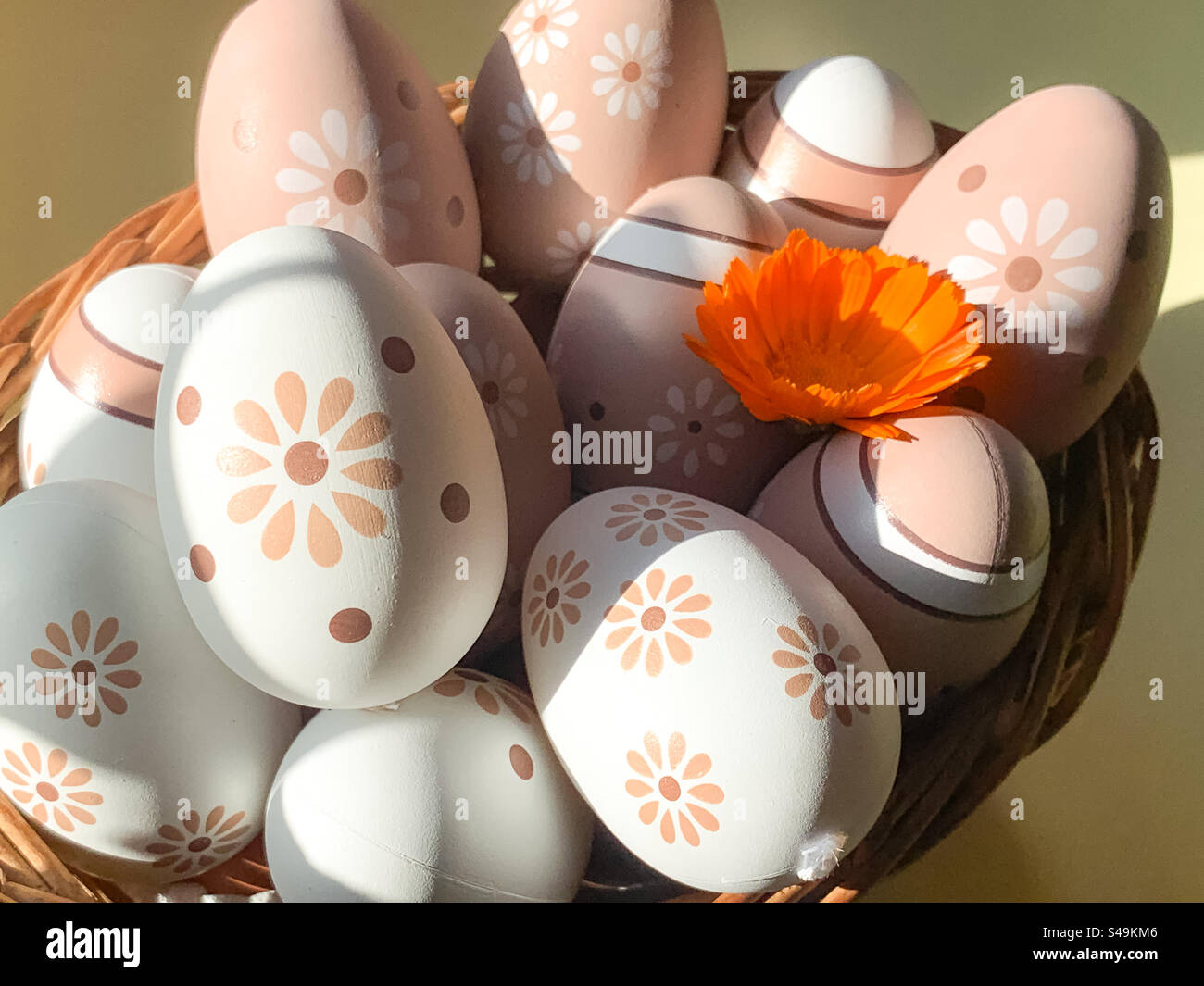 A basket of decorated eggs with an orange pot marigold flower - Smartphone Captured Stock Image