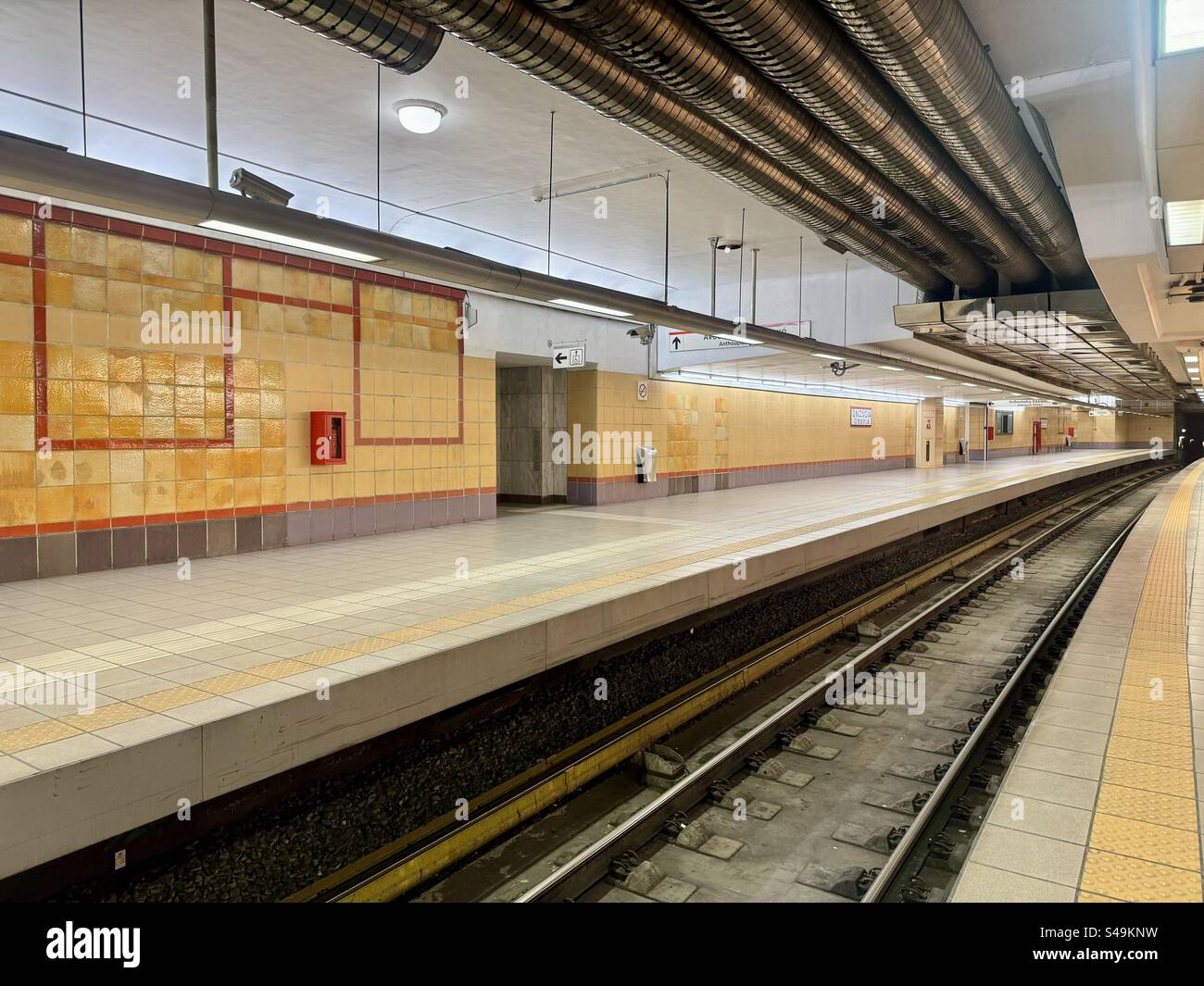 Empty platform at Omonia subway station in Athens, Greece, featuring tiled walls and overhead piping. - Smartphone Captured Stock Image