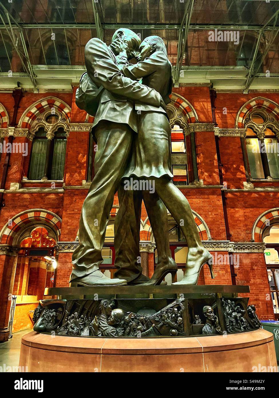 'The Lovers statue', or ‘The meeting place statue’ by sculptor Paul Day at the London railway station St Pancras with its gothic Victorian architecture in the background - Smartphone Captured Stock Image