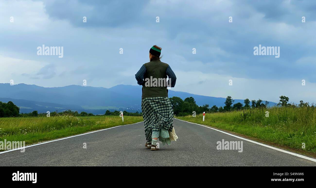 woman walking in the middle of the street in the countryside - Smartphone Captured Stock Image