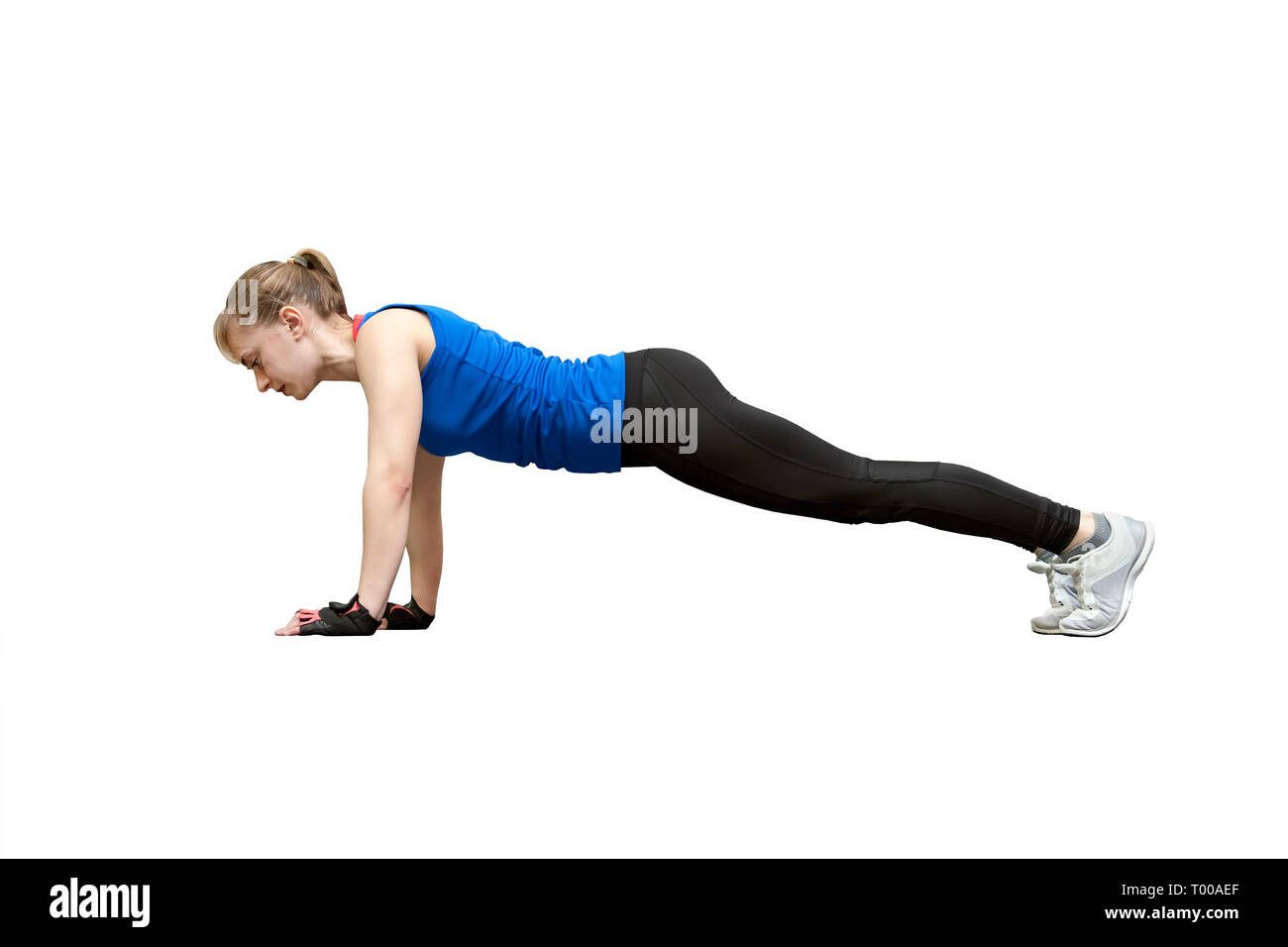young beautiful woman doing push up exercise isolated on white background. Athlete in a blue shirt and black leggings involved in sports. Stock Photo